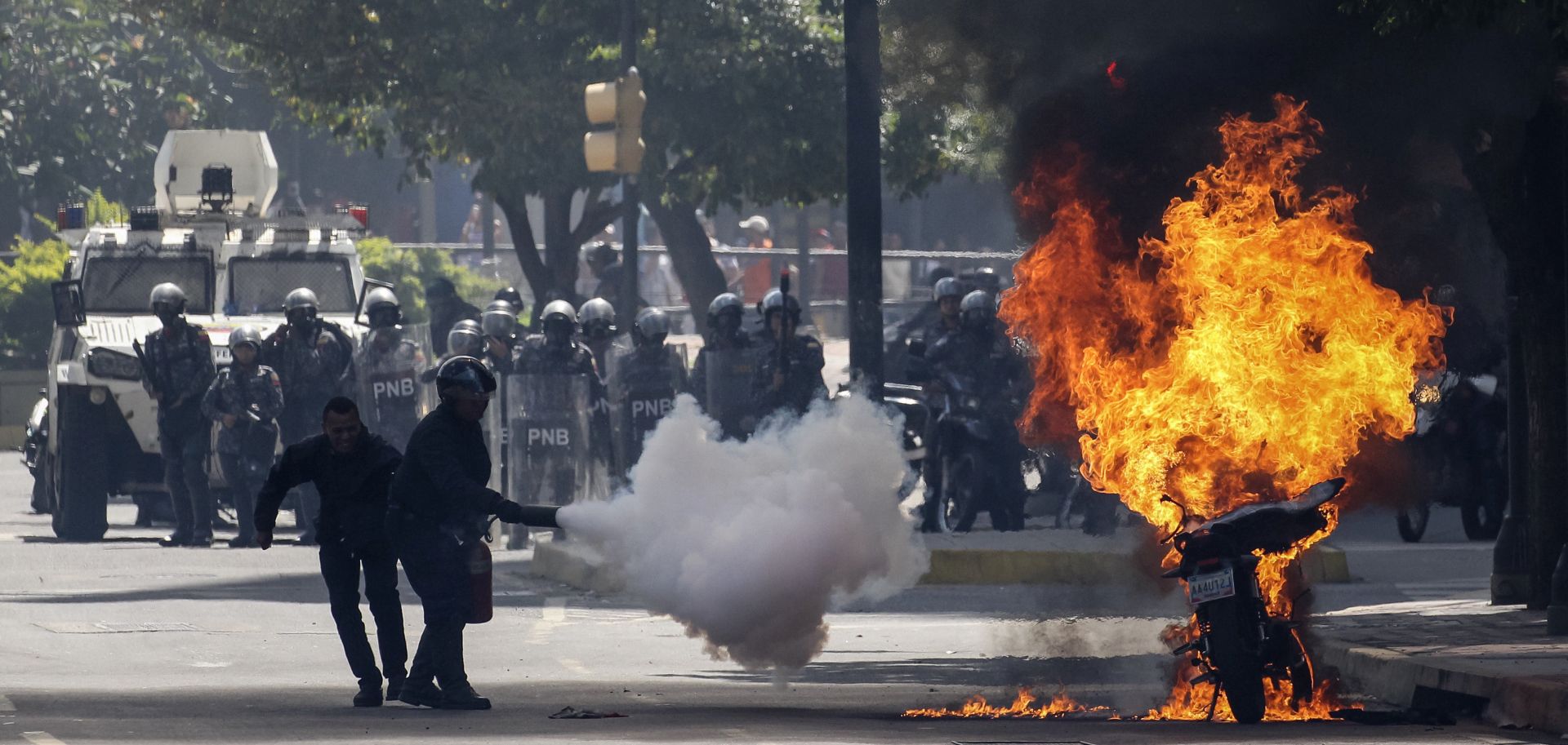 epa06125221 Police try to extinguish a burning motorcycle burns as opposition demonstrators protest the National Constituent Assembly in Caracas, Venezuela, 04 August 2017. Venezuela is installing the 500 member assembly denounced by opposition groups and international leaders and which will rewrite the constitution.  EPA/Miguel Gutierrez