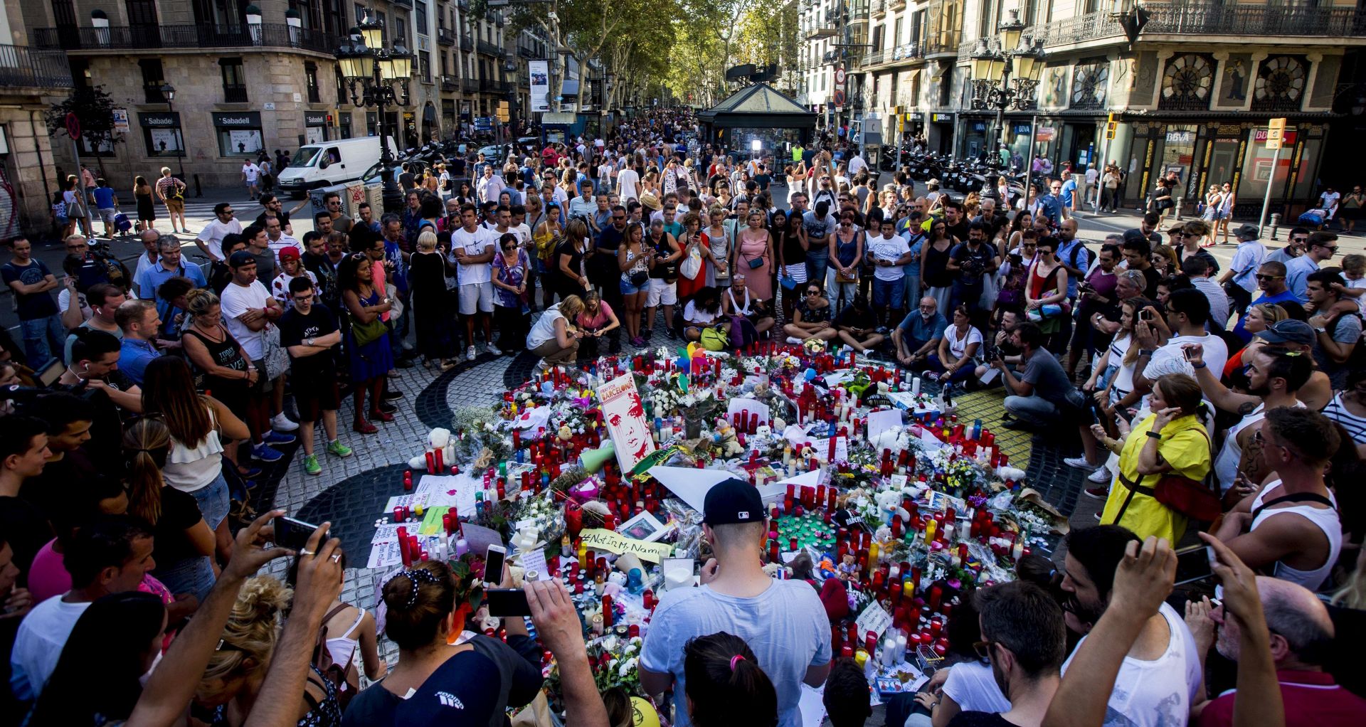 epa06150255 People pay tribute to victims outside the Liceu Theatre, on the site of a deadly van attack in Barcelona, Spain, 18 August 2017. According to media reports, at least 14 people have died and 130 were injured when a van crashed into pedestrians in Las Ramblas, downtown Barcelona in an incident which Spanish police are treating as a terror attack. Similar attack was conducted in coastal city of Cambrils, where five alleged terrorists, who apparently wore bomb belts, were shot dead by security forces on early morning 18 August after they attacked pedestrians using a vehicle next to a promenade, killing one and injuring six people, including a police officer. Police have stated that the attack in Barcelona and the attack in Cambrils are linked. The Islamic State (IS) has claimed the responsibility for the attack in Barcelona.  EPA/QUIQUE GARCIA