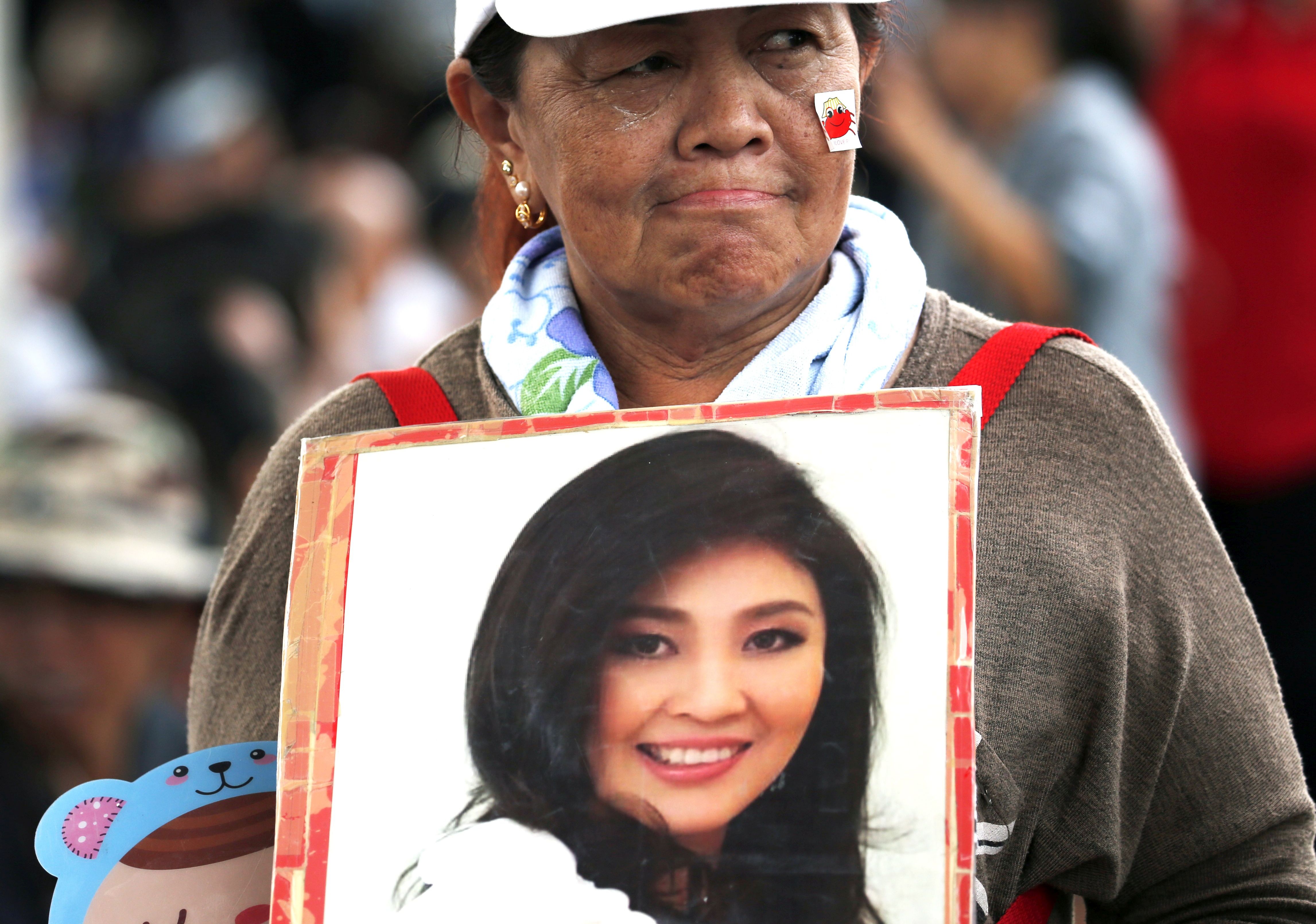 epa06161373 A supporter holds a photograph of former prime minister Yingluck Shinawatra after she failed to appear to hear her verdict at the Supreme Court's Criminal Division for Persons Holding Political Positions in Bangkok, Thailand, 25 August 2017. The Thai court issued an arrest warrant for Yingluck after she failed to appear in court for her verdict and set the new verdict date for 27 September 2017 in which she stands accused on charges of criminal negligence to stop corruption in her government's controversial rice-pledging scheme. Yingluck, who was overthrown in a 2014 military coup, will face up to 10 years in prison if the court finds her guilty.  EPA/RUNGROJ YONGRIT