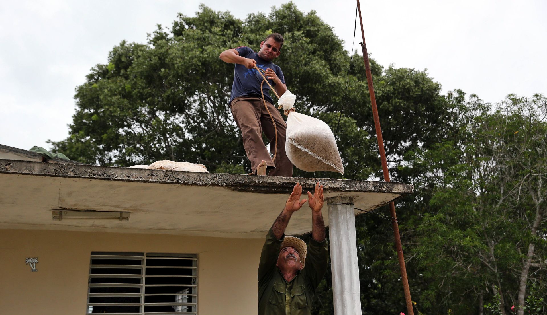 epa06192999 Two men reinforce the roof of a house with sandbags  in preparation for the arrival of Hurricane Irma, in the town of Turiguano, in the province of Ciego de Avila, Cuba, 08 September 2017.   A second hurricane, Jose, may also threaten the area.  EPA/ALejandro Ernesto