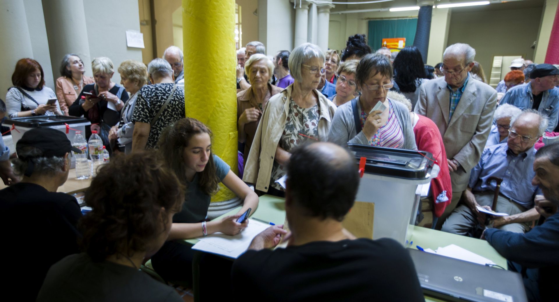 epa06237914 Election officials use cell phones to check voter registration lists as Catalonians wait to cast their vote in the Catalonian referendum, inside a school in Barcelona, Spain, 01 October 2017. Catalonia is holding an independence referendum which has been declared illegal by the Spanish Constitutional Court.  EPA/JIM HOLLANDER