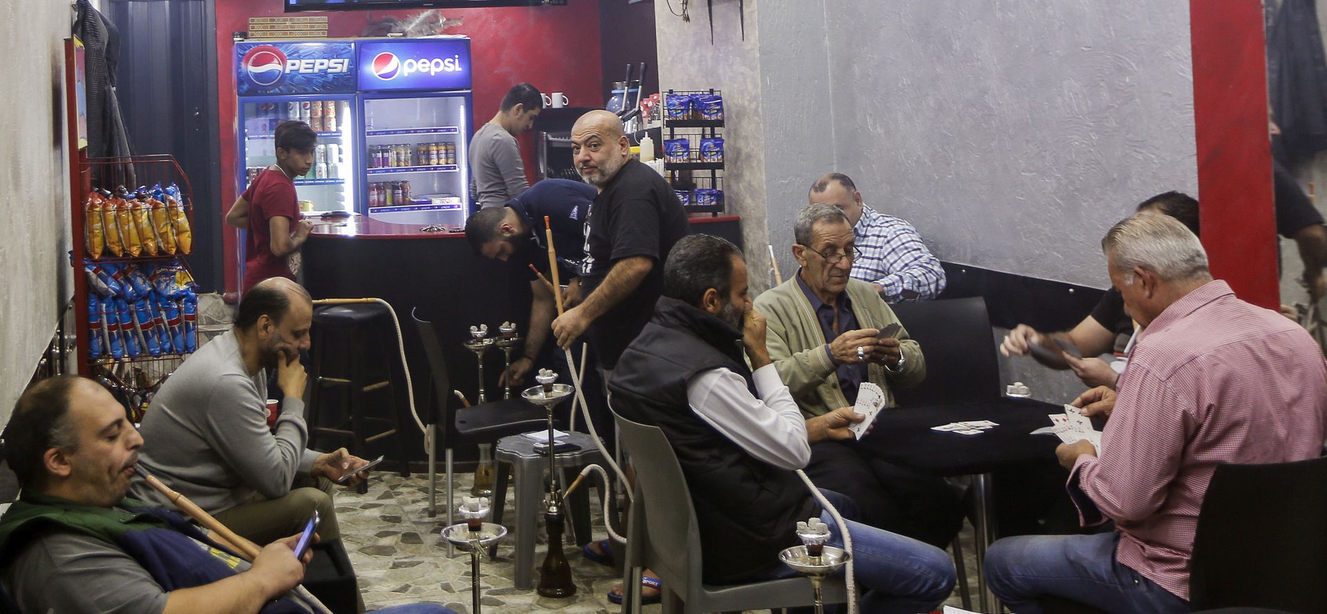 epa06310456 Lebanese men play card and smoke Shisha while listening to the speech of Hezbollah Leader Hassan Nasrallah on TV at a coffee shop in Beirut, Lebanon, 05 November 2017. Lebanese Prime Minister Saad Hariri Announced on 04 Novermber 2017 that he resigns from the Prime Minister's office. According to media reports, Hariri said that the current political climate reminds him with the time before the assassination of his father, former Lebanese Prime Minister Rafic Hariri, and he also mentioned Iran's influence in his country, and the region. Hariri came into office for his second term on 18 December 2017. Nasrallah said in a televised speech that the resignation of Saad Hariri is a decision that came from Saudi Arabia, and that its reasons are not clear to anyone in Lebanon. And he asked his supporters and all the Lebanese parties and All political currents in the country to remain calm and maintain civil peace, and added that Saudi Arabia is interfering in the affairs of Lebanon and is working to undermine its civil peace.  EPA/NABIL MOUNZER