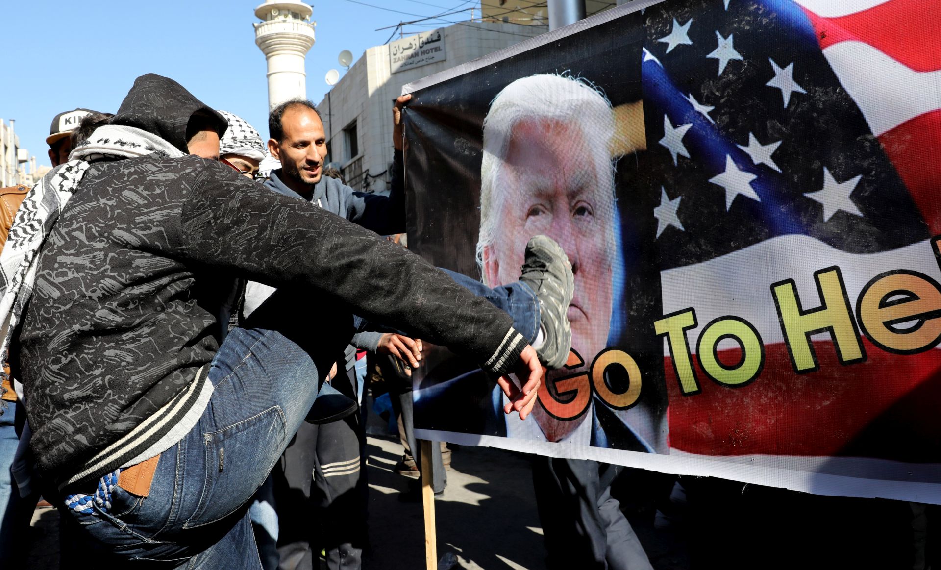 epa06377447 A protesters kicks on a a poster of US President Donald Trump at the start of an anti-Trump anti-Israel march in Down Town Amman, Jordan, 08 December 2017. Palestinians announced general strike and a rage day to protest against US President Donald J. Trump declaration recognizing Jerusalem as the capital of the Israel.  EPA/AMEL PAIN