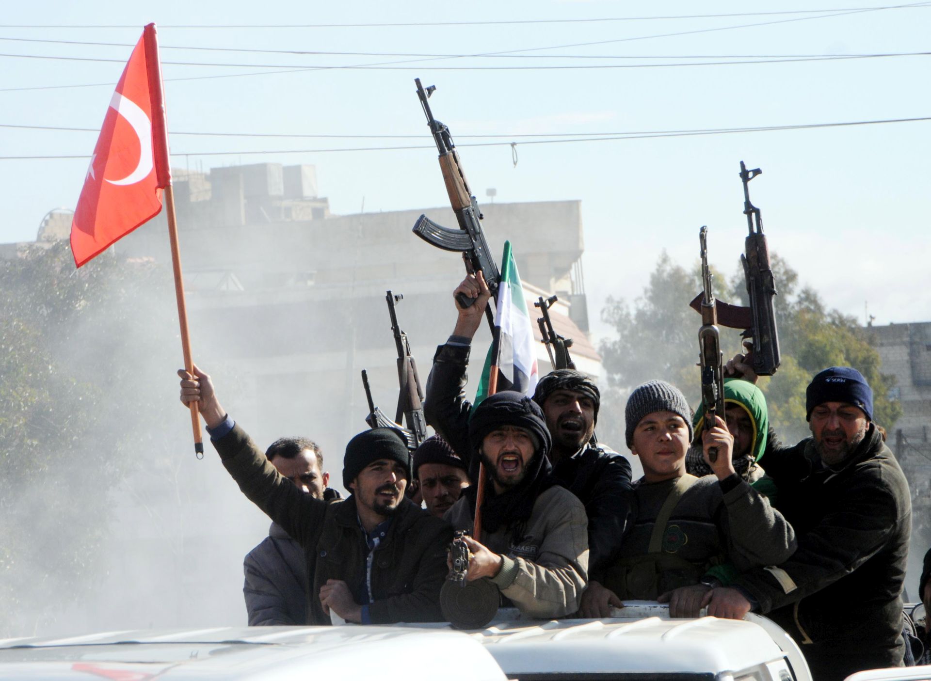 epa06454810 Members of Free Syrian Army (Turkey-backed) fighters tour with their guns as they hold Turkish and their flag in the Syria city of Azez, near the Syrian-Turkish border, 19 January 2018. Report state that the Turkish army is preparing for an operation in Syria against the Kurdish Popular Protection Units (YPG) forces.  EPA/HASAN KIRMIZITAS