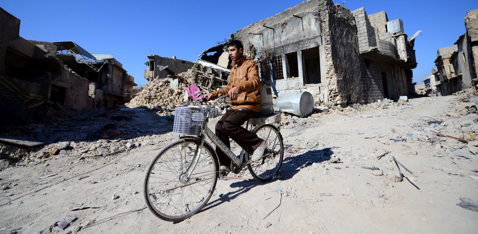 epa06494006 An Iraqi man rides his bicycle next to destructed houses at the old city area, in the west side of Mosul city, Iraq, 02 February 2018 (Issued 03 February 2018). The Iraqi joint forces in December 2017 declared victory over IS after a three-year war against the extremists that caused 3.2 million of civilians to flee from their houses in three Sunni-majority provinces and destroyed more than 60 percent of the cities.  EPA/MURTAJA LATEEF