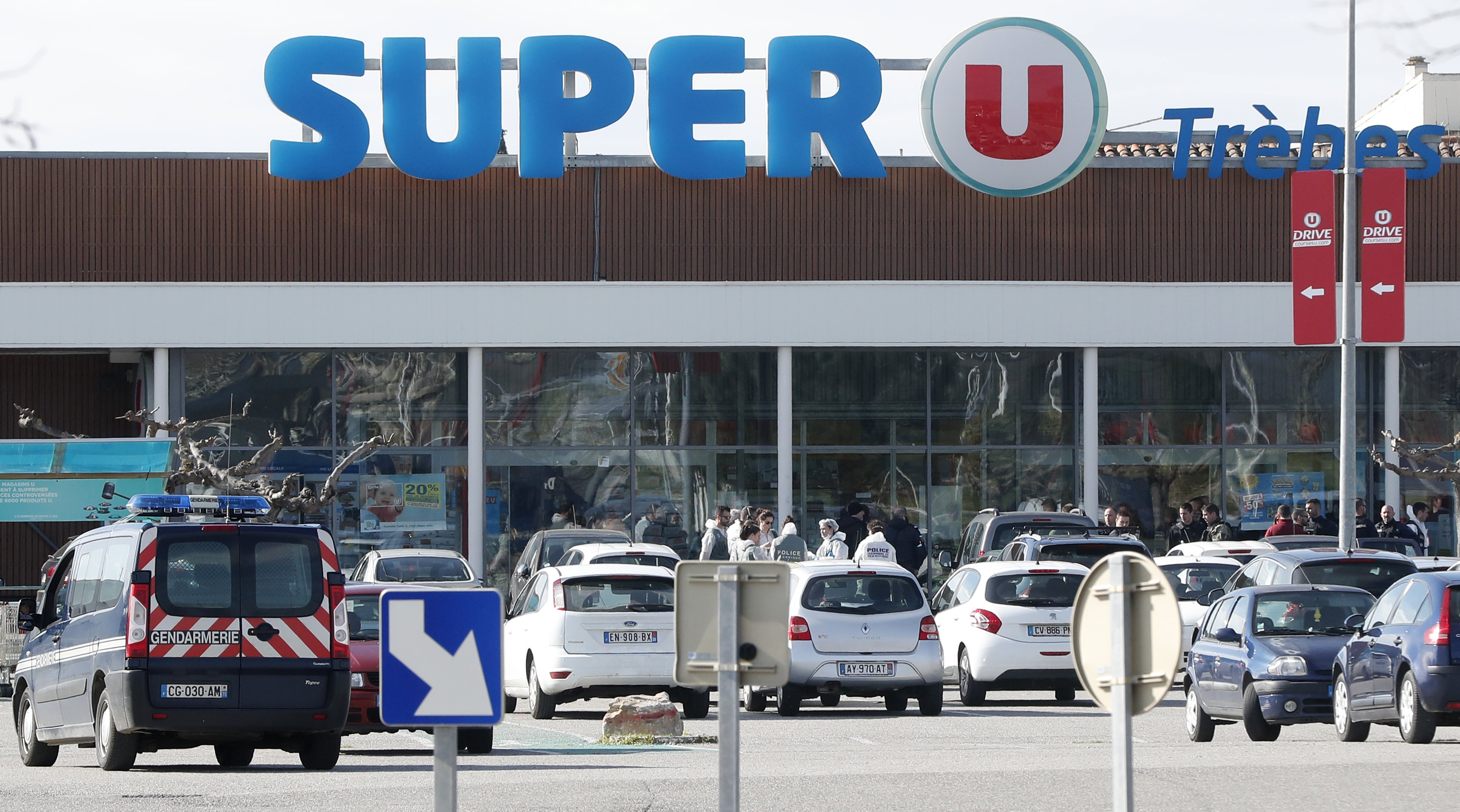 epa06623934 Gendarmes secure the entrance to the Super U supermarket where a gunman claiming allegiance to the Islamic State (IS) holding hostages in Trebes, southern France, 23 March 2018. French police are launching a raid on the supermaket where a gunman that allegedly pledged alliance to the IS is holding hostages. Police says at least two people died and dozens were injured in Trebes near Carcassonne.  EPA/GUILLAUME HORCAJUELO