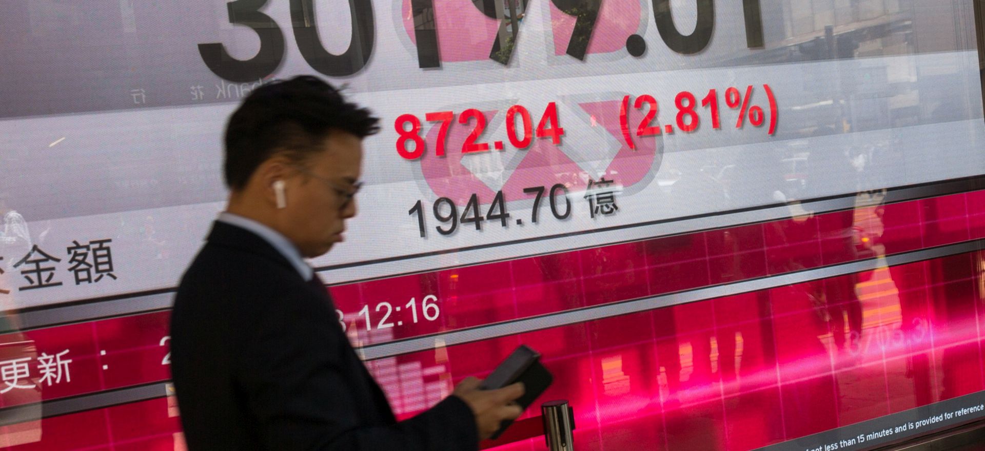 epa06622448 A man walks past an electronic board showing the Hang Seng Index figure in Hong Kong, China, 23 March 2018. Hong Kong and Chinese stock markets were hammered before mid-day by fears of a trade war after Donald Trump imposed sanctions on billions of dollars worth of Chinese goods and Beijing unveiled a tit-for-tat list.  EPA/JEROME FAVRE