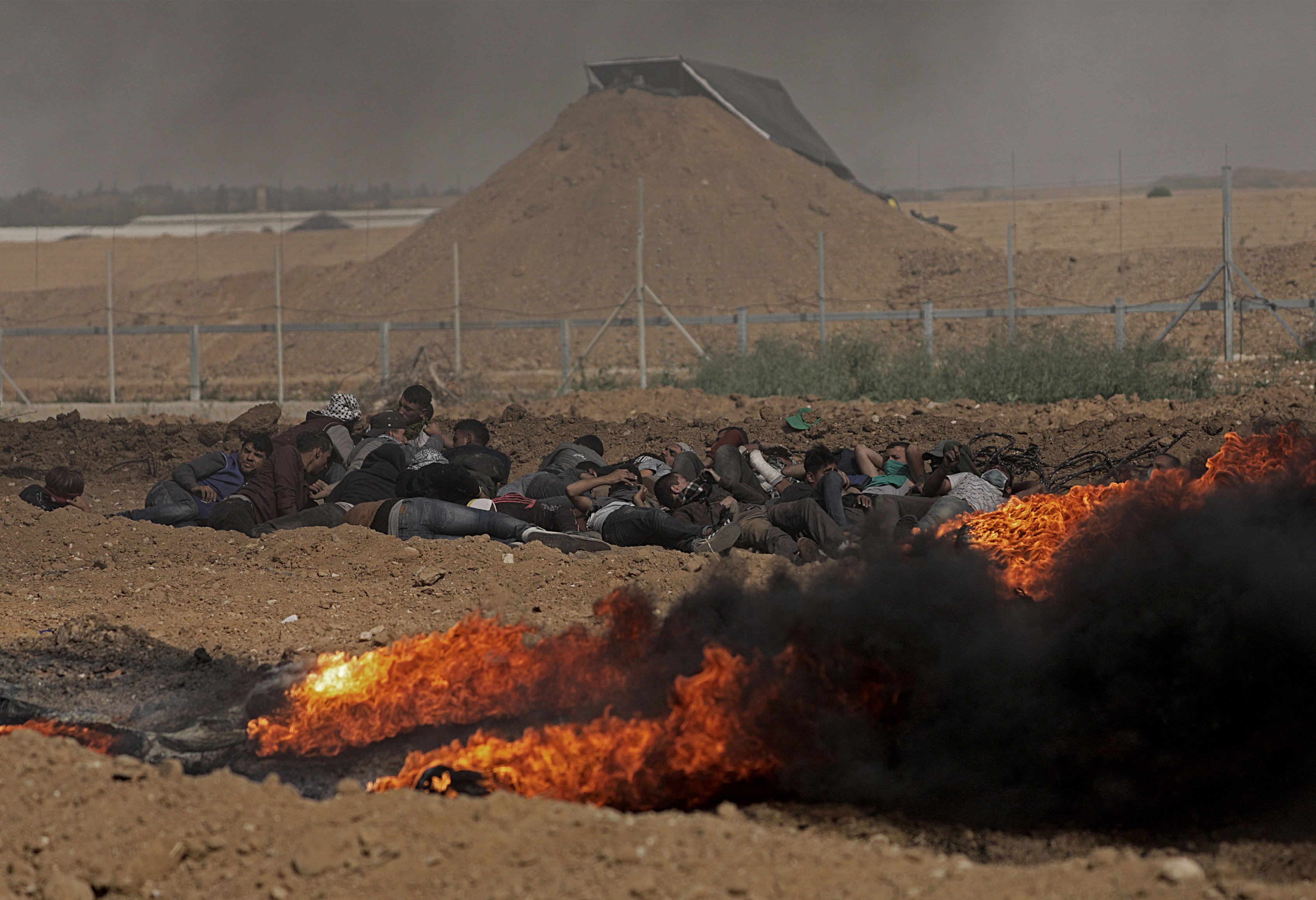 epa06668629 Palestinians protesters take cover during clashes with Israeli troops near the border with Israel in the east of Gaza City on, 13 April 2018 (issued 14 April 2018). According to local sources, more than 700 Palestinians were injured during fresh clashes in the east Gaza Strip near the border with Israel. Thousands of Palestinians in the Gaza strip protested on 13 April as part of the so-called Great March of Return demonstration for the third consecutive week along Gaza's border with Israel, calling for the right of Palestinian refugees and their descendants to return to their homelands. Since the beginning of the Great March of Return on 30 March, riots have been taking place near the Gaza-Israeli border, to which the Israeli army has responded with crowd control and live ammunition.  EPA/MOHAMMED SABER