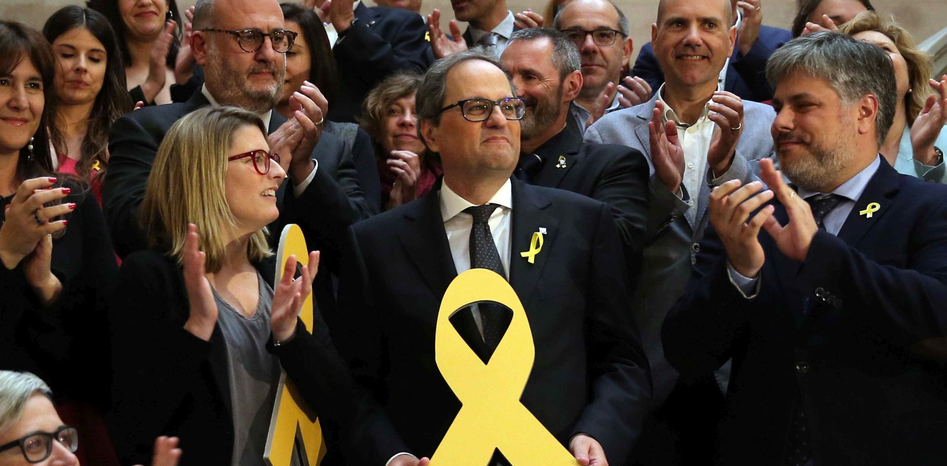 epa06736020 New Catalan regional Government President, Quim Torra (C), poses with a yellow ribbon as he is congratulated by party members after being elected by simple majority in the second and last investiture session at the regional Parliament in Barcelona, northeastern Spain, 14 May 2018.  EPA/Toni Albir