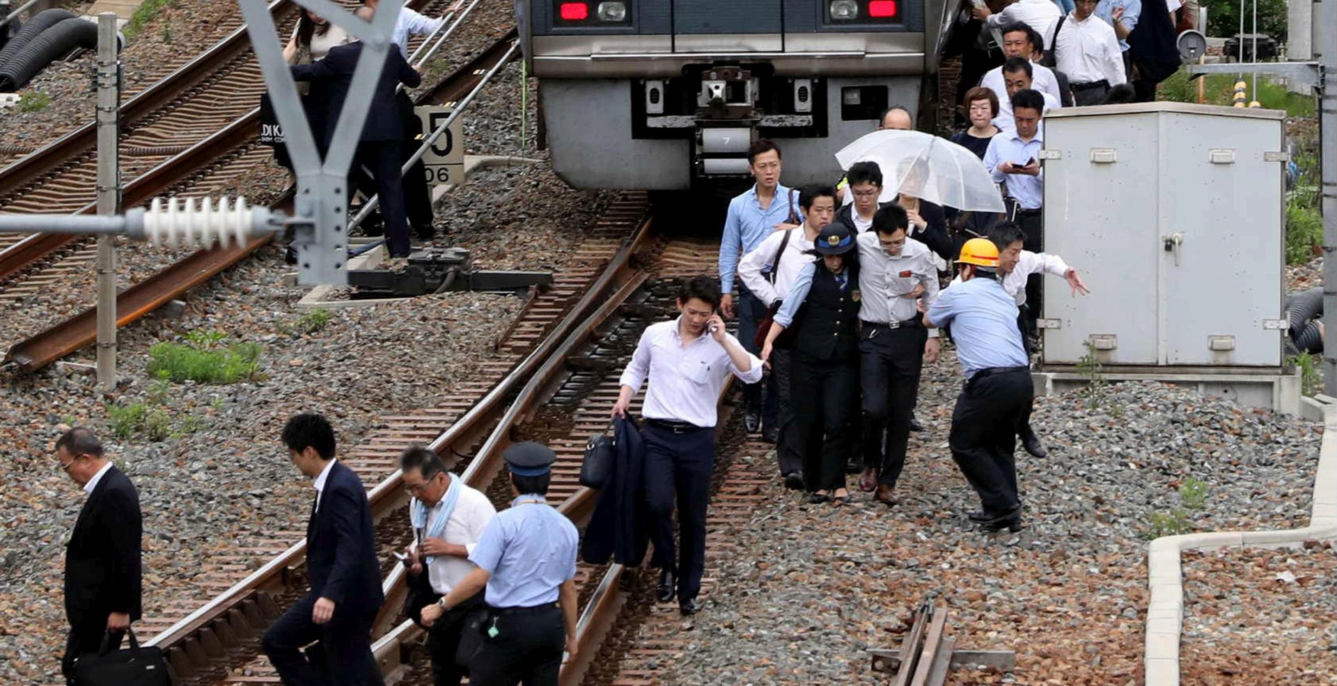 epa06817532 Passengers on board a commuter train walk on the railway due to suspended service, after a magnitude 6.1 earthquake hit western Japan, in Osaka, western Japan, 18 June 2018.  EPA/JIJI PRESS EDITORIAL USE ONLY/NO ARCHIVE/JAPAN OUT  EDITORIAL USE ONLY