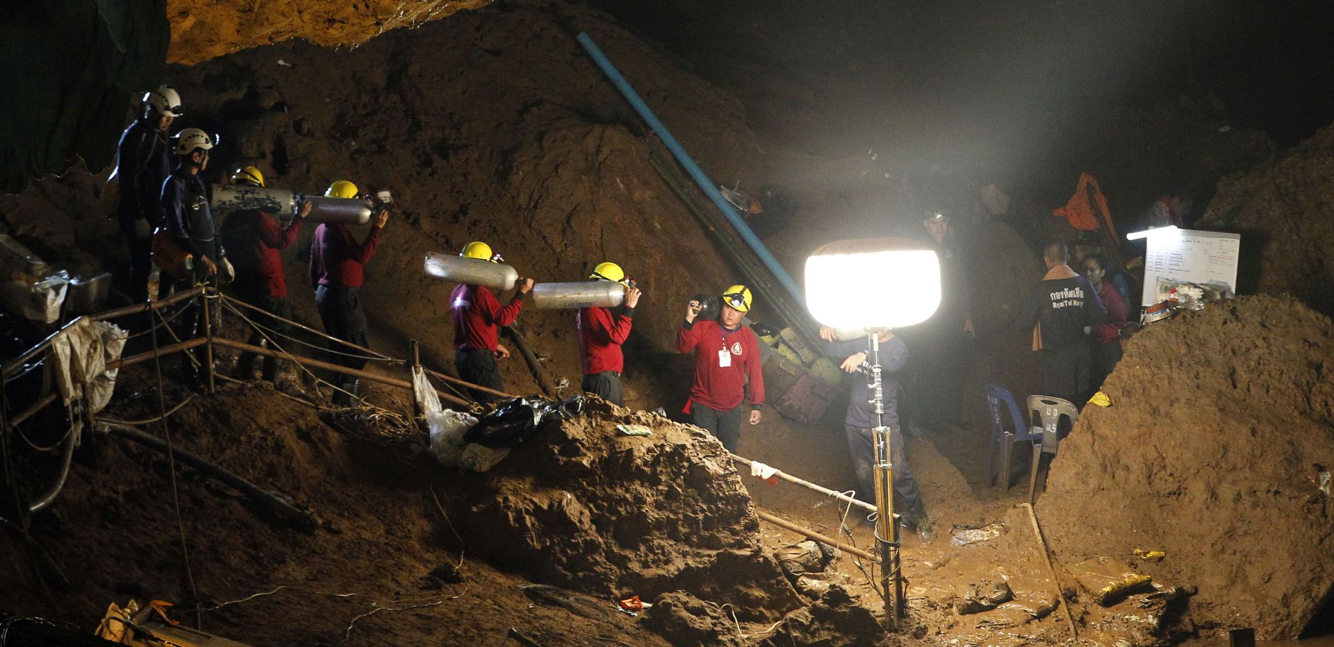 epa06853964 Thai officials carry oxygen tanks through a cave complex during a rescue operation for a missing football team at the Tham Luang cave in Tham Luang Khun Nam Nang Noon Forest Park in Chiang Rai province, Thailand, 30 June 2018. Rescuers are attempting to pump water out of a cave complex in an effort to rescue 12 members of a youth soccer team that are believed to have been trapped in the flooded cave complex since 23 June.  EPA/PONGMANAT TASIRI