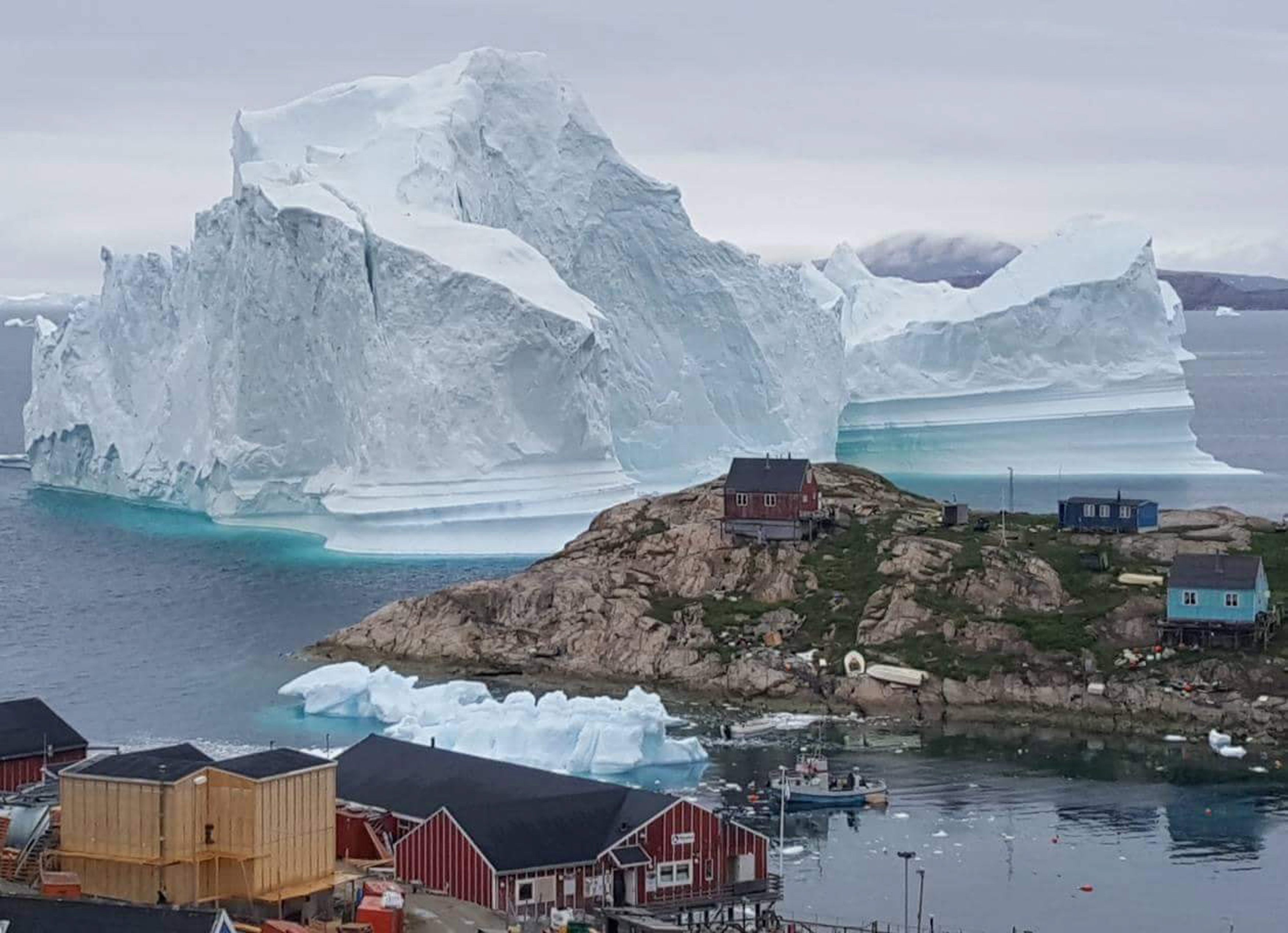 epa06885114 A general view shows an iceberg stranded near the village of Innaarsuit, in the Avannaata Municipality, northwestern Greenland, 12 July 2018 (issued 13 July 2018). The Avannaata Municipality was alarmed on 11 July, after a huge iceberg was grounded just outside the village of Innaarsuit. According to local media, police asked villagers who live closest to the water, to leave their houses over fears the iceberg could calve and affect the village with a tsunami.  EPA/KARL PETERSEN  DENMARK OUT
