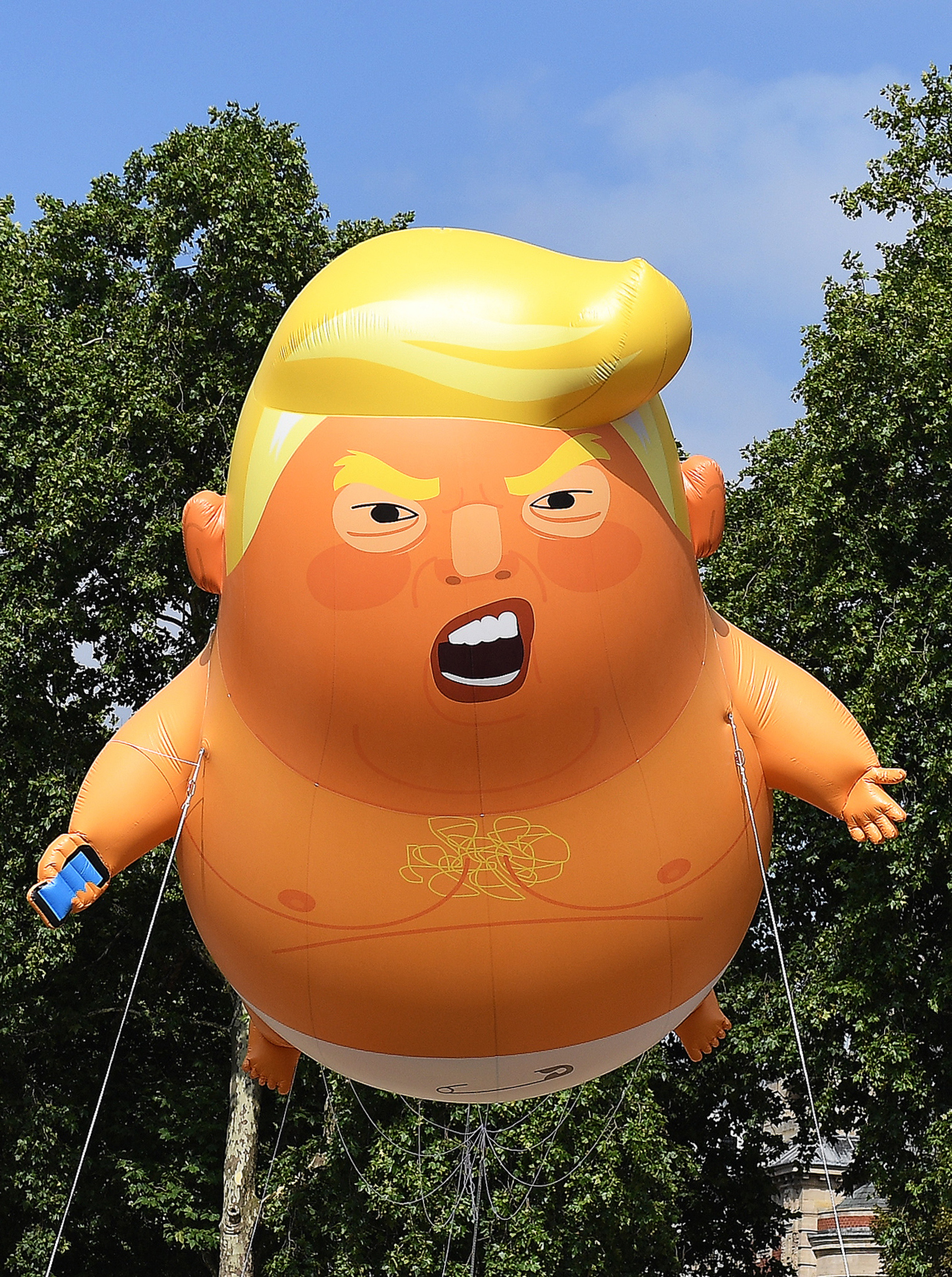 epa06885294 The 'Donald Trump Baby Blimp' balloon flies over Parliament Square during a protest in London, Britain, 13 July 2018. The inflatable dubbed 'Trump Baby' tied to a spot in Parliament Square is to kick off a day of protests against US President Donald J. Trump's visit. Trump is on a working visit to Britain.  EPA/ANDY RAIN