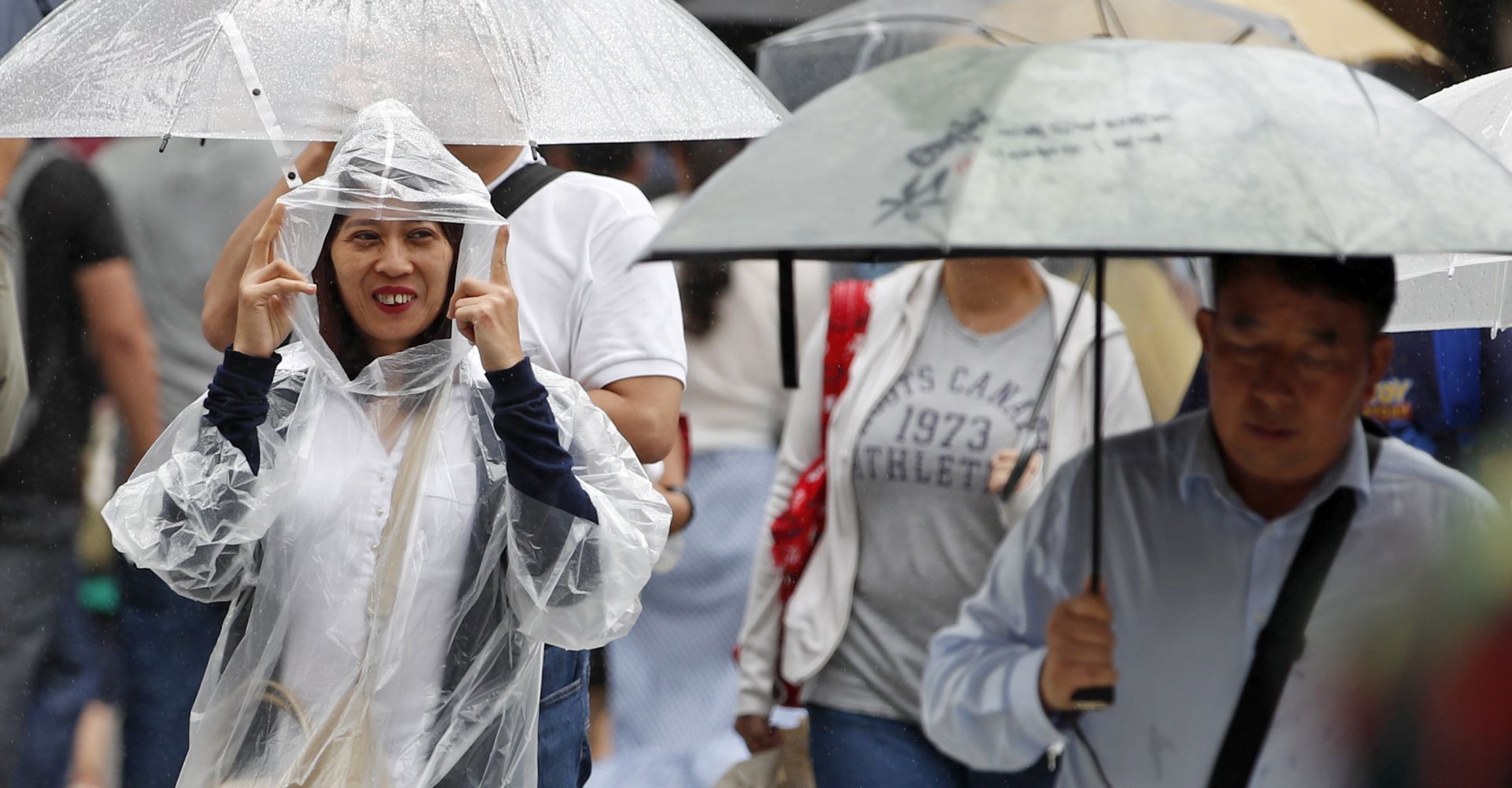 epa06935051 A woman protects herself from rain and wind generated by typhoon Shanshan in Tokyo, Japan, 08 August 2018. Typhoon Shanshan is forecasted to approach Tokyo area overnight.  EPA/FRANCK ROBICHON