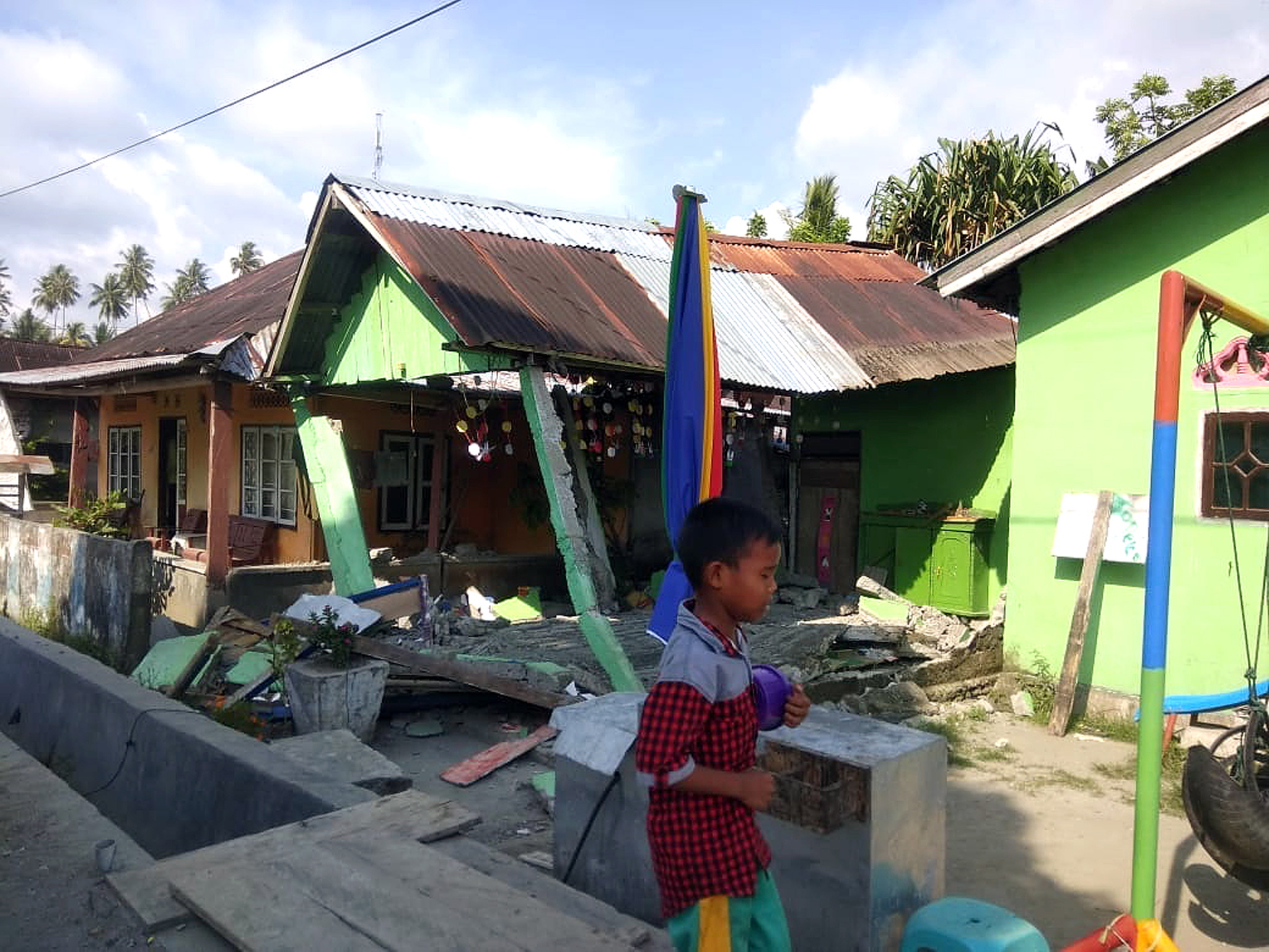 epa07054030 A handout photo made available by the Indonesian National Board for Disaster Management (BNPB) shows a boy walking in front of a collapsed house after a 6.1 magnitude earthquake that hit in Donggala, Central Sulawesi, Indonesia, 28 September 2018. According to BNPB, a series of powerful earthquakes has hit Central Sulawesi killing at least one person and injuring dozens.  EPA/BNPB HANDOUT -- BEST QUALITY AVAILABLE -- HANDOUT EDITORIAL USE ONLY/NO SALES