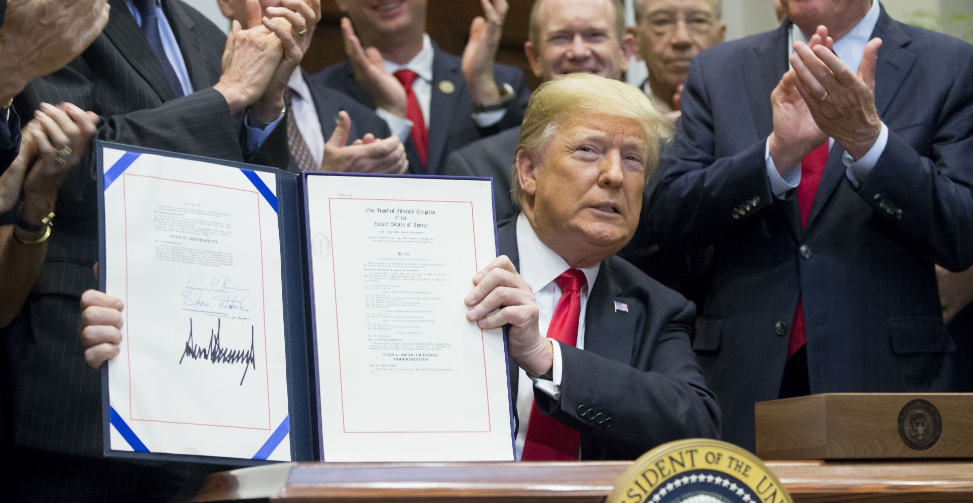 epa07086784 US President Donald J. Trump (C) holds up the 'Orrin G. Hatch-Bob Goodlatte Music Modernization Act', after signing it during a ceremony in the Roosevelt Room of the White House in Washington, DC, USA, 11 October 2018. The act is aimed at updating music copyright law for the digital era.  EPA/MICHAEL REYNOLDS