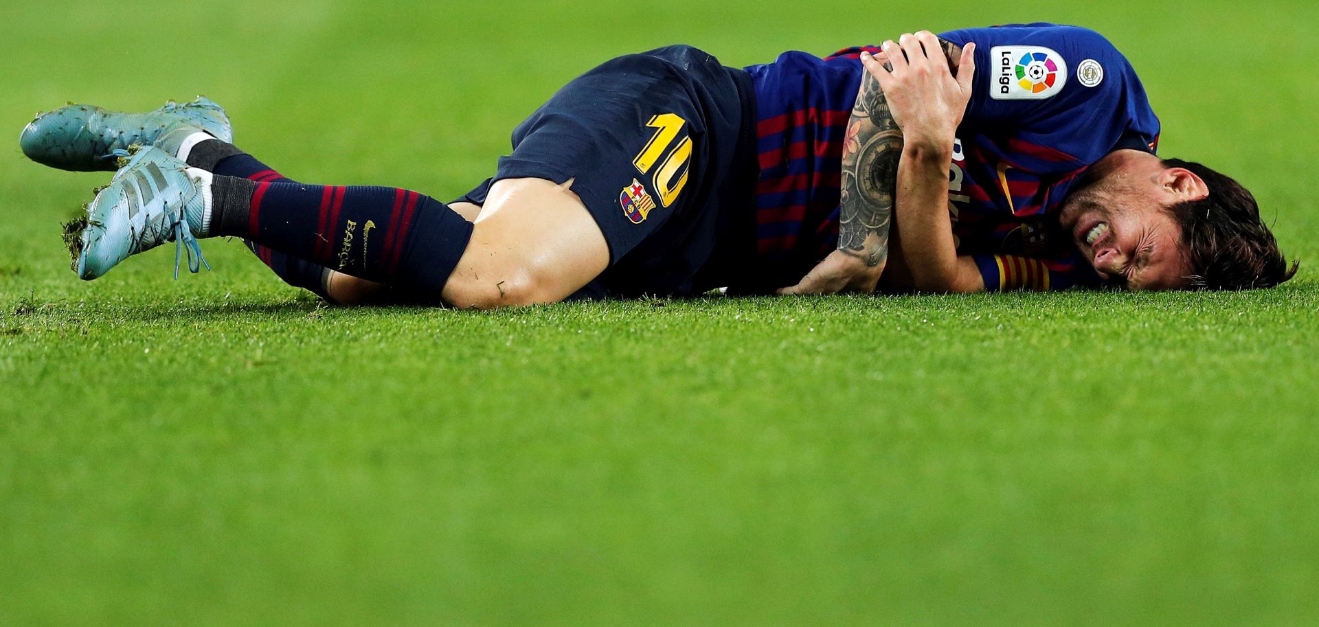 epa07108058 FC Barcelona's Lionel Messi lies on the pitch after sustaining an injury during the Spanish La Liga soccer match between FC Barcelona and Sevilla CF at Camp Nou stadium in Barcelona, Spain, 20 October 2018. Messi broke his arm in the match and will miss the Clasico.  EPA/ALEJANDRO GARCIA