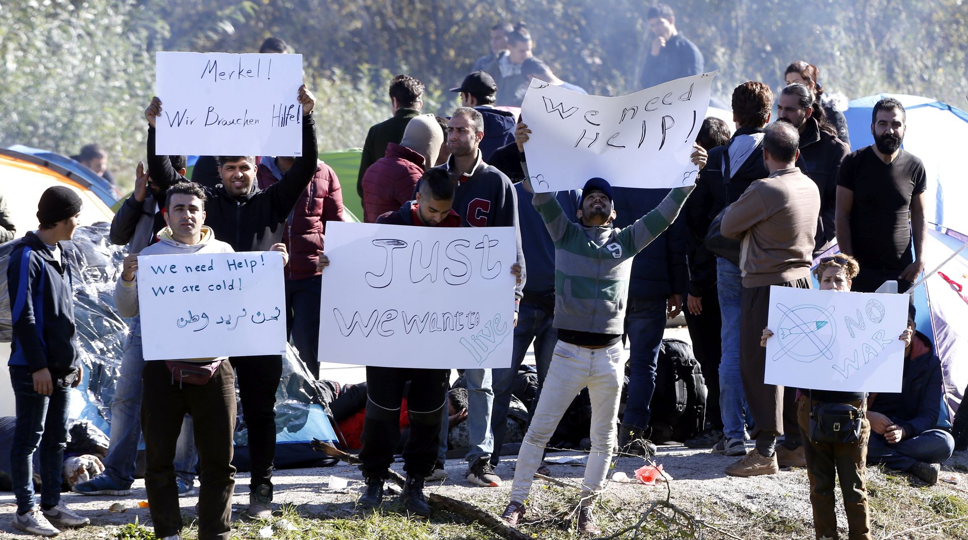 epa07119013 A group of migrants attempting to cross into Croatia hold banners as they gather near the Maljevac border crossing, Bosnia and Herzegovina, 25 October 2018. According to reports, a group of some 100 migrants mostly from Afghanistan, Pakistan, and Iraq attempting to cross into Western Europe erected tents at the border area to pressure neighboring Croatia to open border and let them travel north. Thousands of migrants and refugees fleeing wars and poverty in Asia and North Africa are sleeping rough in impoverished Bosnia, and many are growing concerned about the onset of cold winter weather and a lack of adequate shelters.  EPA/FEHIM DEMIR
