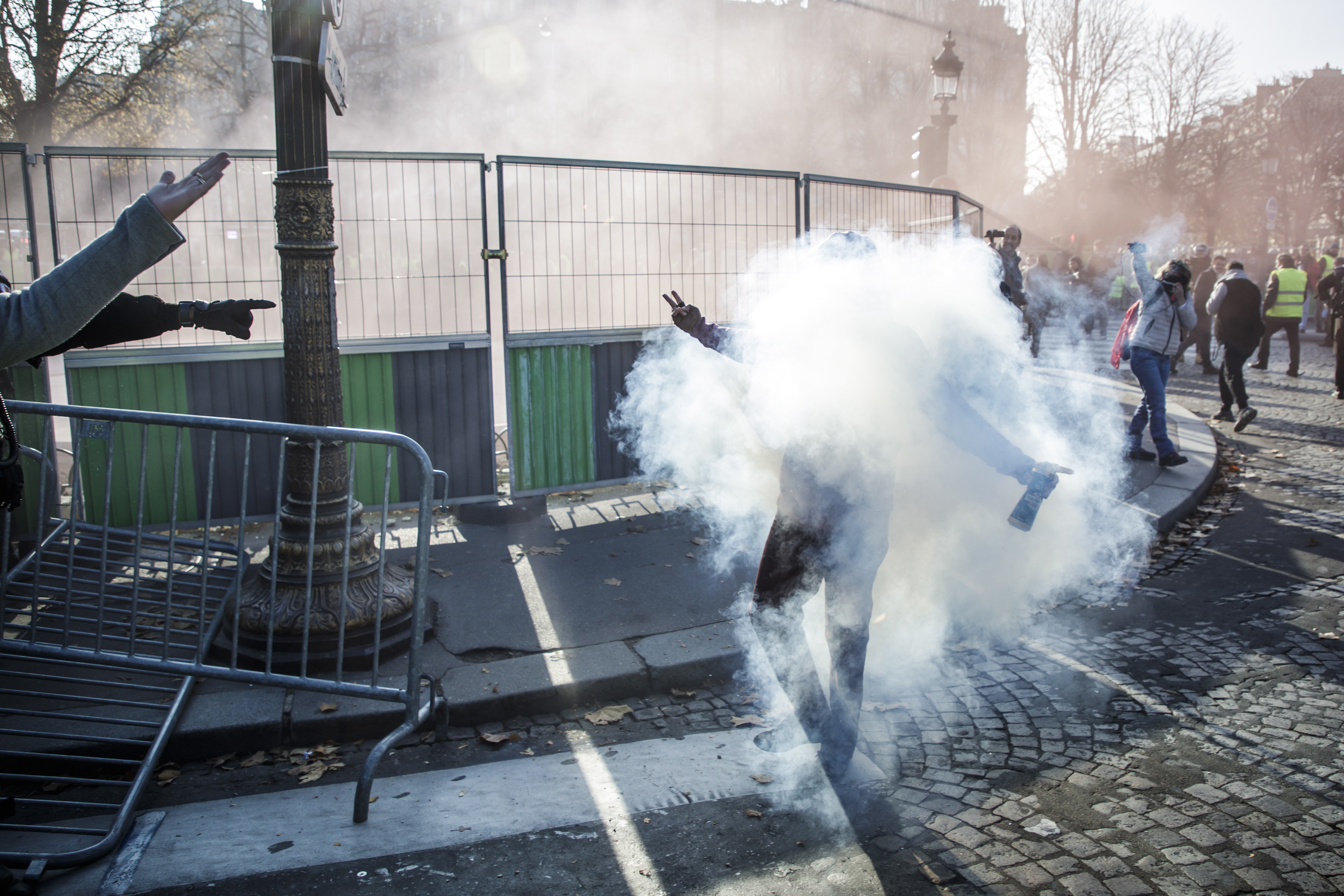 epa07173141 Police forces use tear gas against people wearing  yellow vests, as a symbol of French driver's and citizen's protest against higher fuel prices, during a demonstration on the Champs Elysee as part of a nationwide protest in Paris, France, 17 November 2018. The so-called 'gilets jaunes' (yellow vests) protest movement, which has reportedly no political affiliation, is protesting over fuel prices. According to reports, a female protester died after she was ran over by a vehicle in the south-eastern Savoy region as others were injured elsewhere during nationwide demonstrations.  EPA/CHRISTOPHE PETIT TESSON