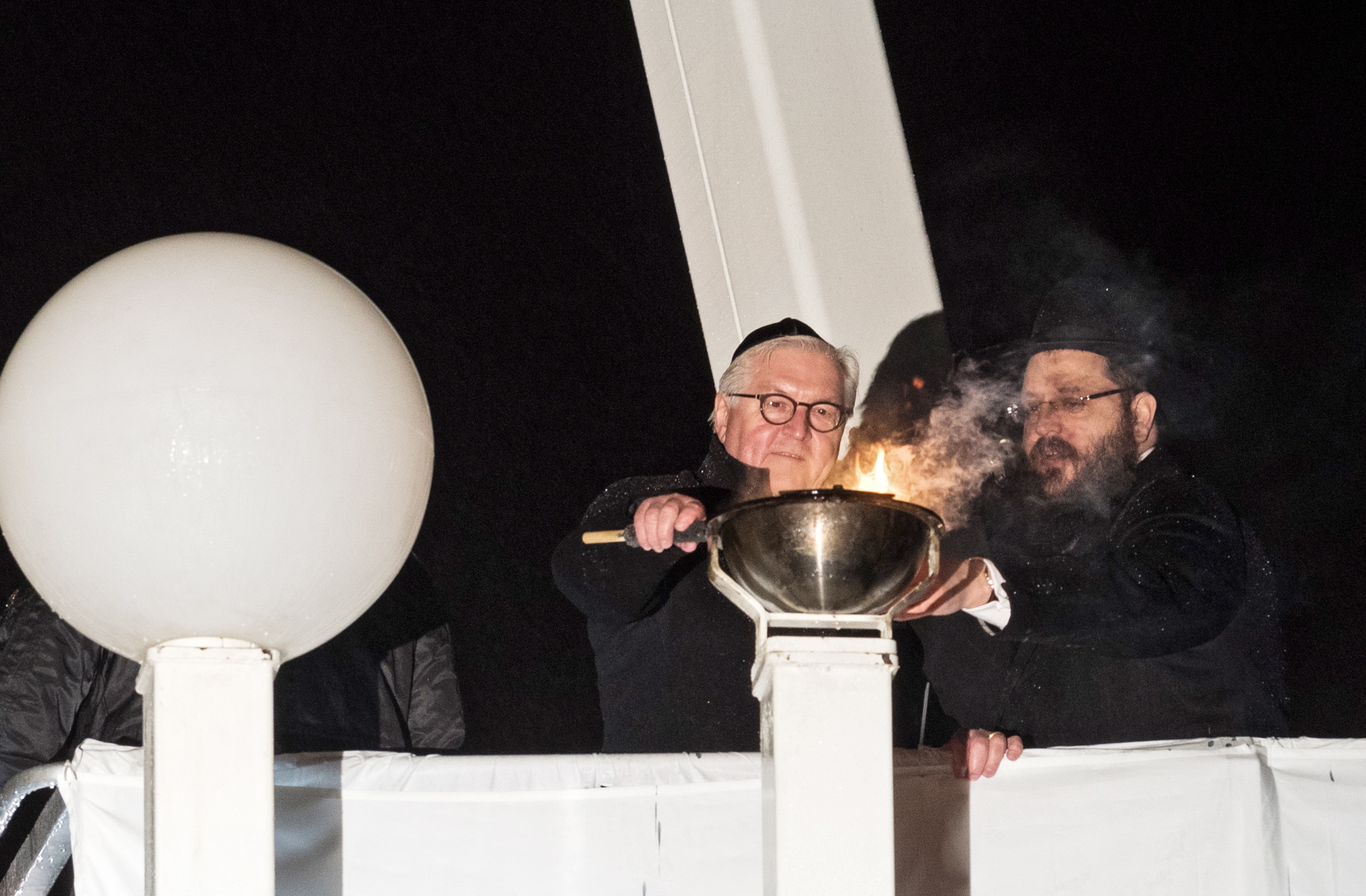 epa07204535 German President Frank-Walter Steinmeier (L) and Rabbi of Jewish Community in Berlin Yehuda Teichtal light on the Hanukkah Menorah at the Pariser Platz in front of the Brandenburg Gate in Berlin, Germany, 02 December 2018. Hanukkah, also known as the 'Festival of Lights', is one of the most important Jewish holidays and is celebrated by Jews worldwide.  EPA/MARKUS HEINE
