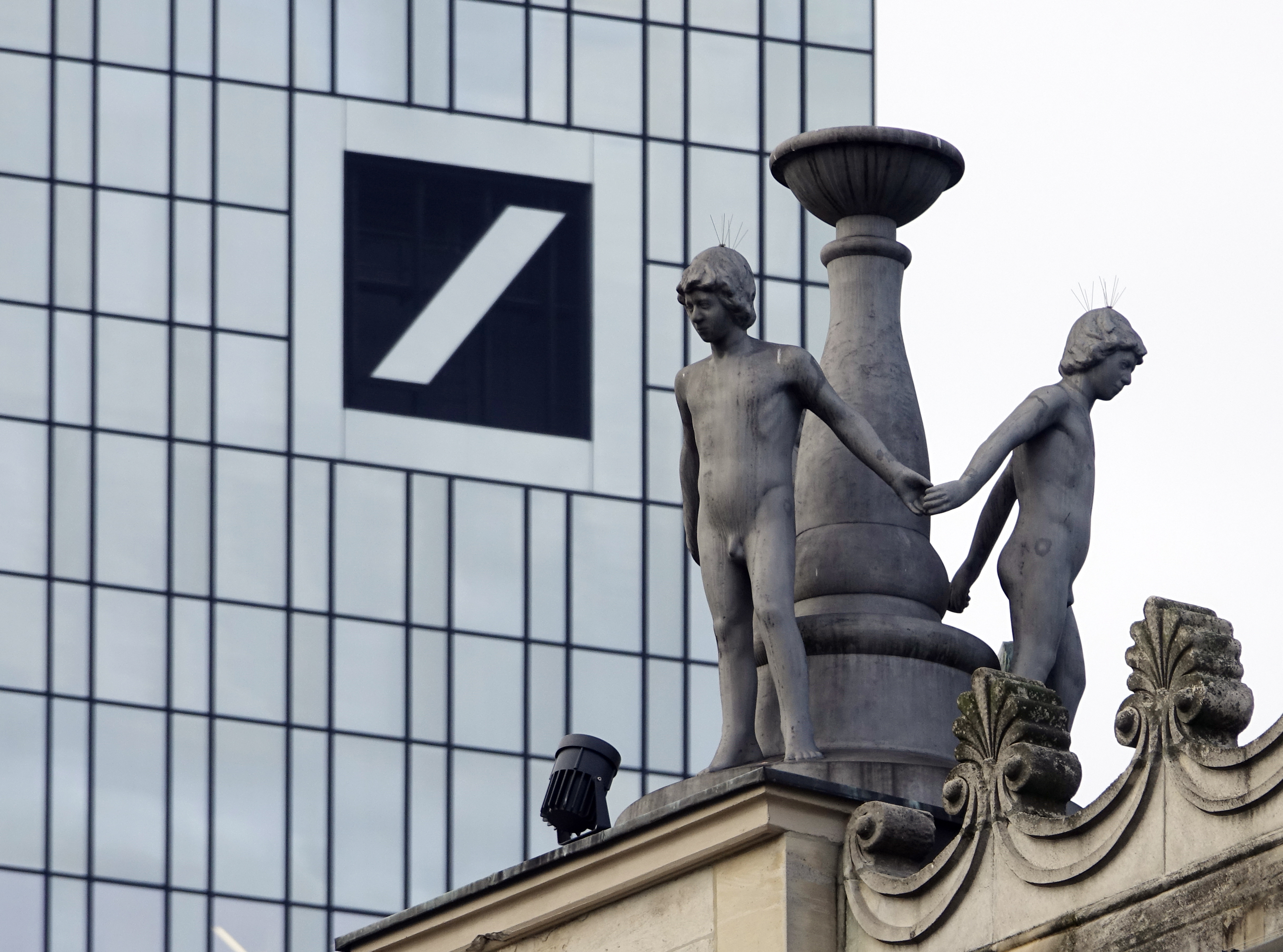 epa07209486 Figures of a statue ensemble at the roof of the Old Opera building in Frankfurt, with the Deutsche Bank building and signage on background, Frankfurt, Germany, 05 December 2018. Reports on 05 December state Deutsche Bank shares fell below 8 euros, a drop of 2.4 per cent, amid criminal investigations into possible money laundering. It is only the second time Deutsche Bank's shares have fallen below 8 euros. The bank offices were raided by police 29-30 November, causing the bank shares to slip below 8 euros lever for the first time.  EPA/MAURITZ ANTIN