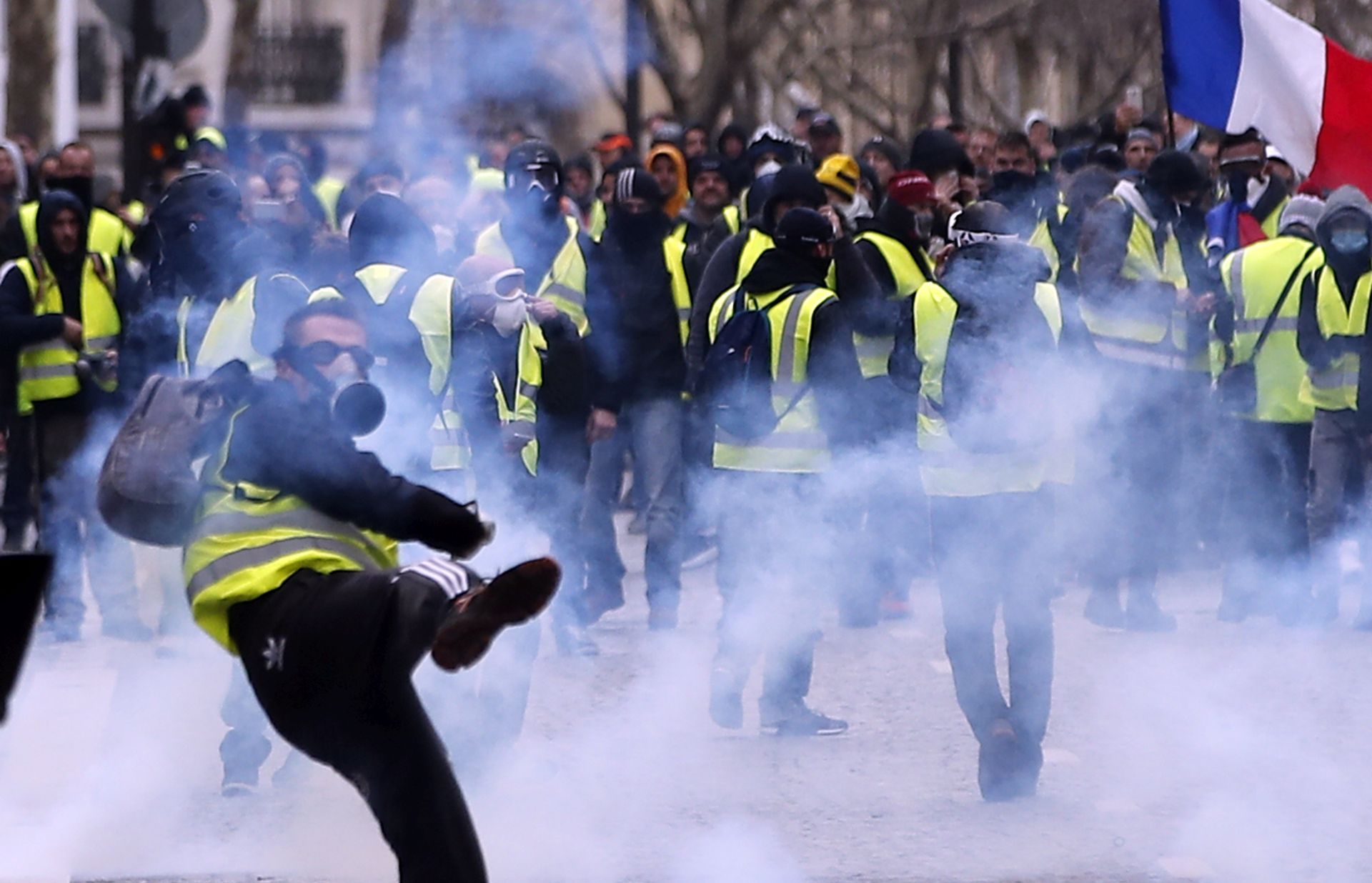 epa07216572 A Yellow Vests protester hurl back tear gas to French riot police during a demonstration in Paris, France, 08 December 2018. Police in Paris is preparing for another weekend of protests of the so-called 'gilets jaunes' (yellow vests) protest movement. Recent demonstrations of the movement, which reportedly has no political affiliation, had turned violent and caused authorities to close some landmark sites in Paris this weekend.  EPA/IAN LANGSDON