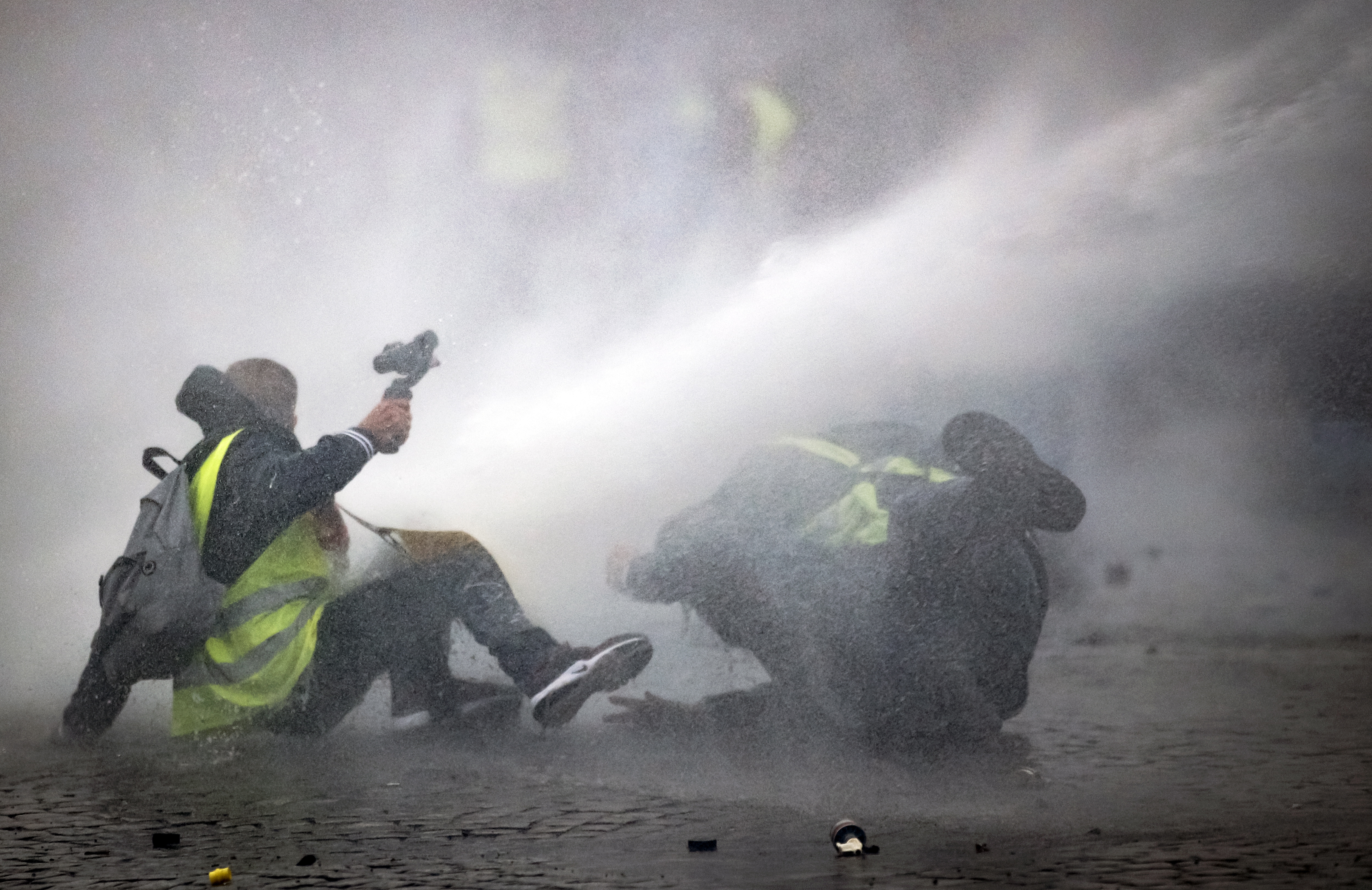 epa07277854 Riot police water canons spray protesters from the 'Gilets Jaunes' (Yellow Vests) movement as they take part in the 'Act IX' demonstration (the 9th consecutive national protest on a Saturday) in front of the Arc de Triomphe in Paris, France, 12 January 2019. The so-called 'gilets jaunes' (yellow vests) is a grassroots protest movement with supporters from a wide span of the political spectrum, that originally started with protest across the nation in late 2018 against high fuel prices. The movement in the meantime also protests the French government's tax reforms, the increasing costs of living and some even call for the resignation of French President Emmanuel Macron.  EPA/YOAN VALAT