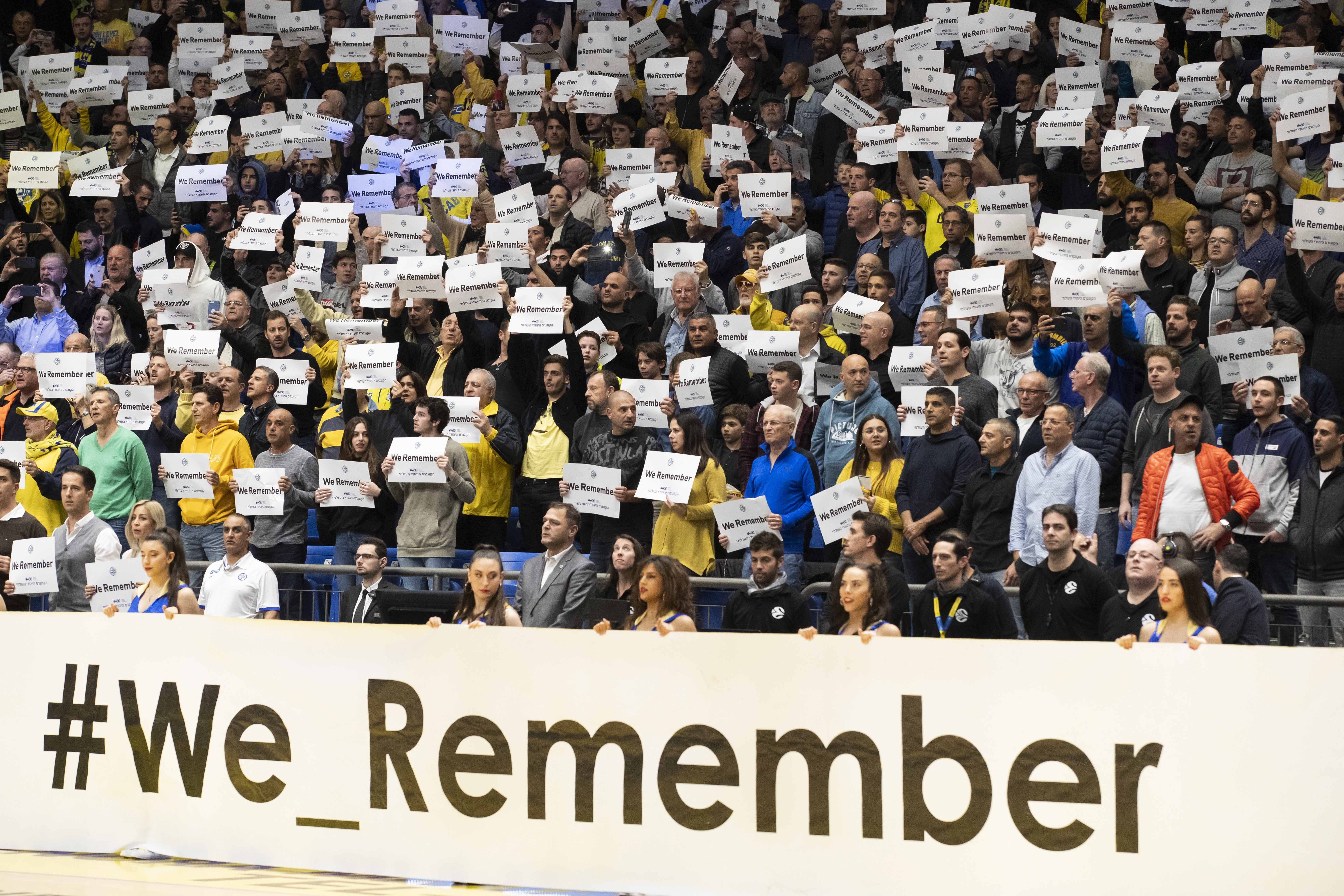 epa07316656 Israelis hold up 'We Remember' placards in the basketball stadium in Tel Aviv, Israel, 24 January 2019 before the start fo the Euroleague basketball match Maccabi Fox Tel Aviv vs Panathinaikos Opap Athens as they mark International Holocaust Remembrance Day.  EPA/JIM HOLLANDER