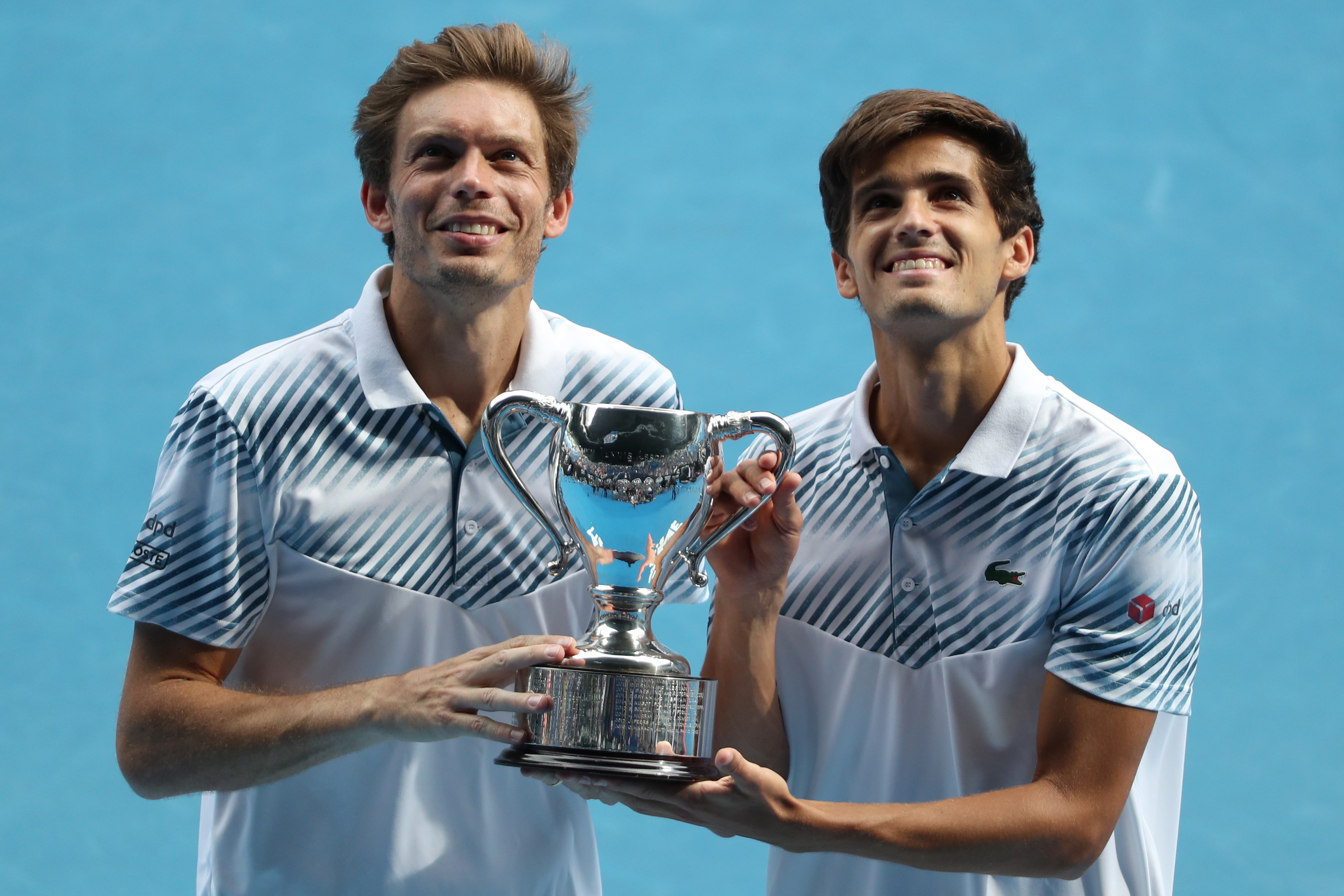 epa07323367 Nicolas Mahut of France (L) and Pierre-Hugues Herbert (R) of France pose for a photograph with the winner's trophy after defeating Henri Kontinen of Finland and John Peers of Australia in the men's doubles final on day fourteen of the Australian Open tennis tournament in Melbourne, Australia, 27 January 2019.  EPA/DAVID CROSLING  AUSTRALIA AND NEW ZEALAND OUT