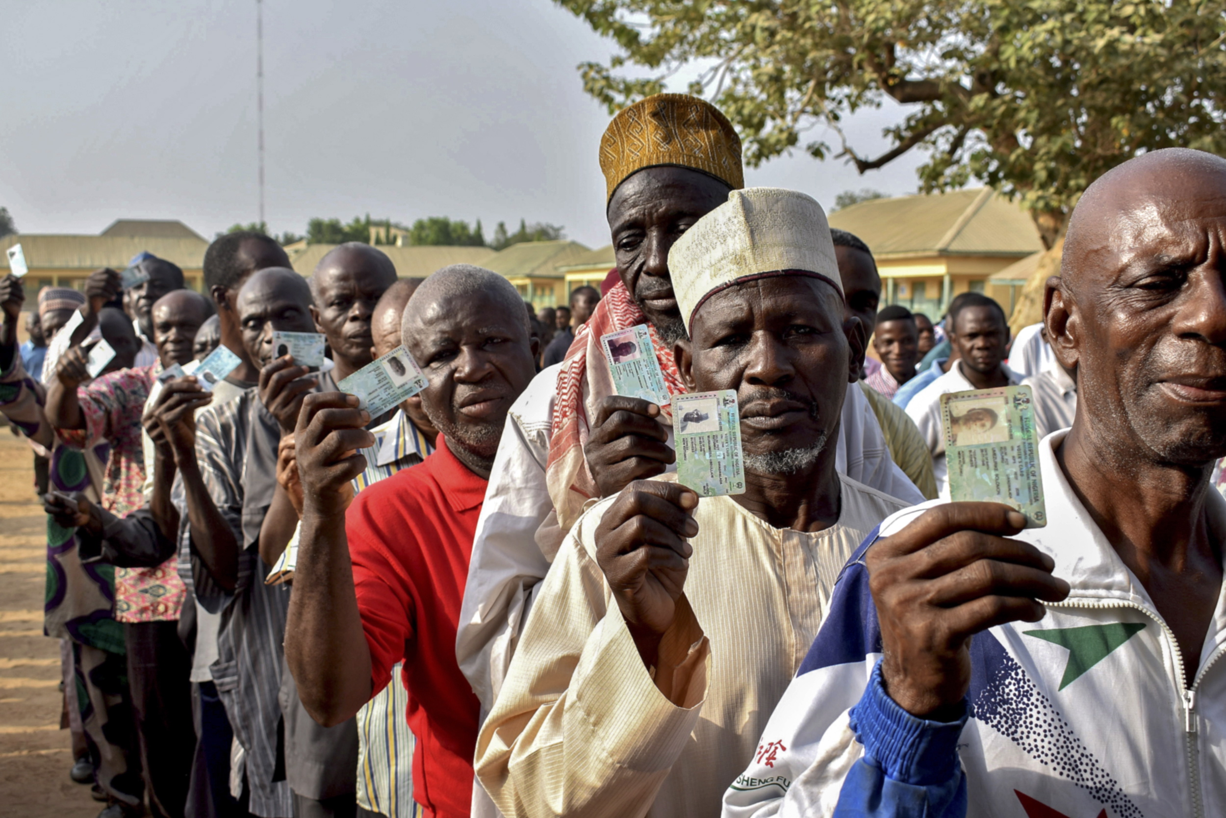 epa07389771 Nigerians display their voter cards as they line up to cast their ballots in the presidential elections in Abuja, Nigeria, 23 February 2019. Nigerians head to the polls to vote in the presidential and parliamentary elections after being delayed by one week by the Independent National Electoral Commission (INEC).  EPA/STR