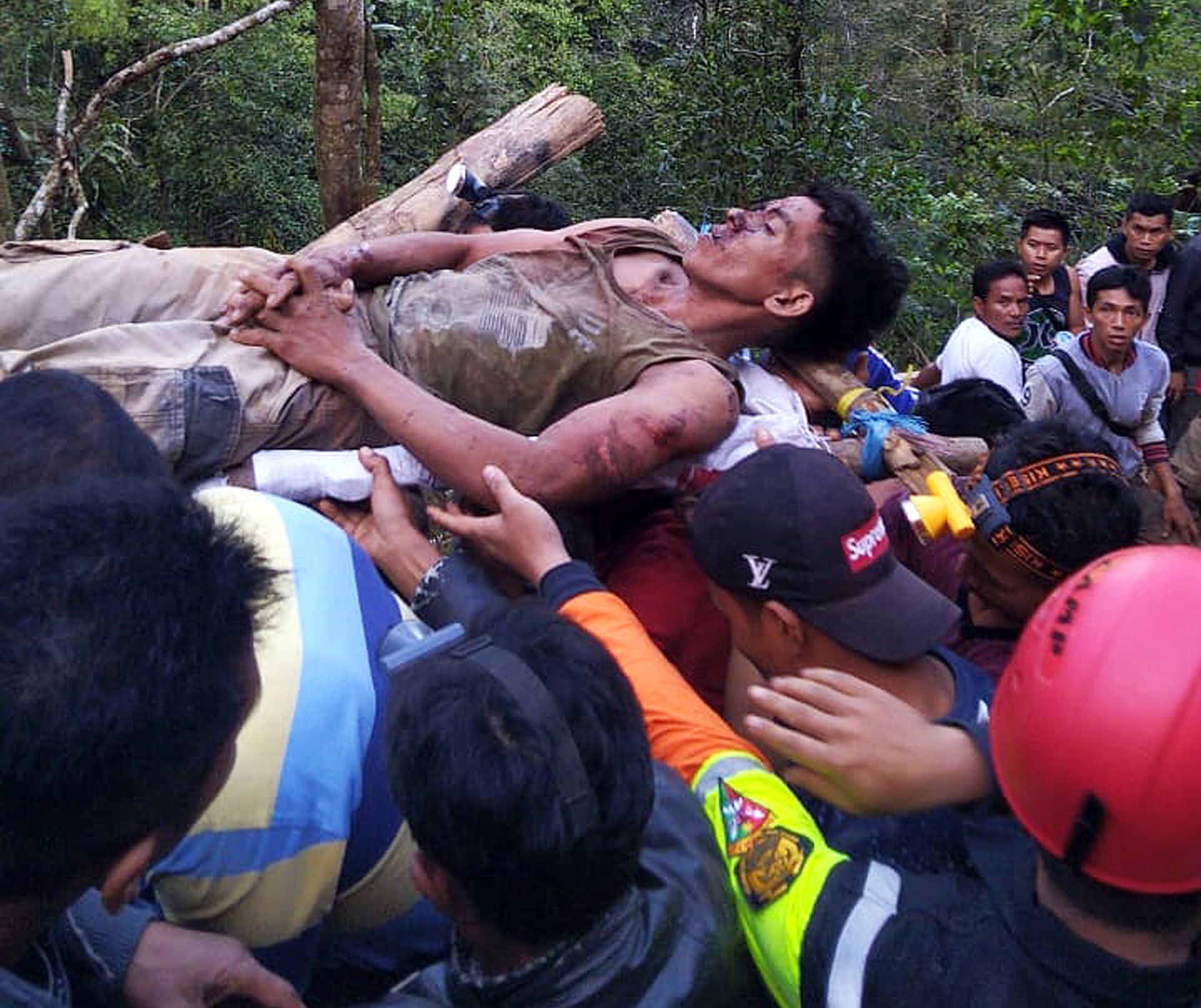 epa07400225 A handout photo made available by Indonesia's search and rescue (BASARNAS) shows rescuers carrying a survivor from a collapsed illegal gold mine in the Bolaang Mongondow region of North Sulawesi, Indonesia, 27 February 2019. A miner died and 60 more are missing in Indonesia after an illegal gold collapsed on the island of Celebes, official sources said. Thirteen other injured people could be rescued at the mine, according to Sutopo Purwo Nugroho, a spokesman for the National Disaster Management Agency.  EPA/BASARNAS MANADO HANDOUT BEST QUALITY AVAILABLE HANDOUT EDITORIAL USE ONLY/NO SALES