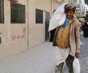 epa07373128 A conflict-affected Yemeni man passing a building with the words in Arabic ‘Yemen is in our hearts’ carries food rations provided by Mona Relief Yemen at a neighborhood in Sana'a, Yemen, 14 February 2019 (issued 15 February 2019). According to reports, the United Nations has warned that the situation in war-torn Yemen is getting even worse as a four-year long conflict between the Saudi-backed government forces and the Houthi rebels has created the worst humanitarian crisis in the world, where some 80 percent of Yemen's 26-million population are in need of humanitarian assistance.  EPA/YAHYA ARHAB