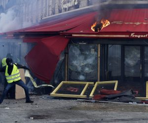 epa07442862 Yellow Vests protesters clash with rior police in front of the Fouquet's restaurant on fire during the 'Act XVIII' demonstration (the 18th consecutive national protest on a Saturday) in Paris, France, 16 March 2019. The so-called 'gilets jaunes' (yellow vests) is a grassroots protest movement with supporters from a wide span of the political spectrum, that originally started with protest across the nation in late 2018 against high fuel prices. The movement in the meantime also protests the French government's tax reforms, the increasing costs of living and some even call for the resignation of French President Emmanuel Macron.  EPA/YOAN VALAT