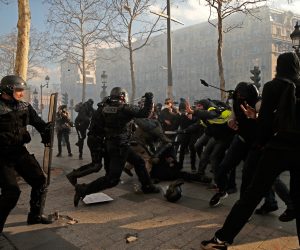 epa07443444 Yellow Vests protesters hit a riot police officer (C down) on the Champs Elysees during the 'Act XVIII' demonstration (the 18th consecutive national protest on a Saturday) in Paris, France, 16 March 2019. The so-called 'gilets jaunes' (yellow vests) is a grassroots protest movement with supporters from a wide span of the political spectrum, that originally started with protest across the nation in late 2018 against high fuel prices. The movement in the meantime also protests the French government's tax reforms, the increasing costs of living and some even call for the resignation of French President Emmanuel Macron.  EPA/YOAN VALAT