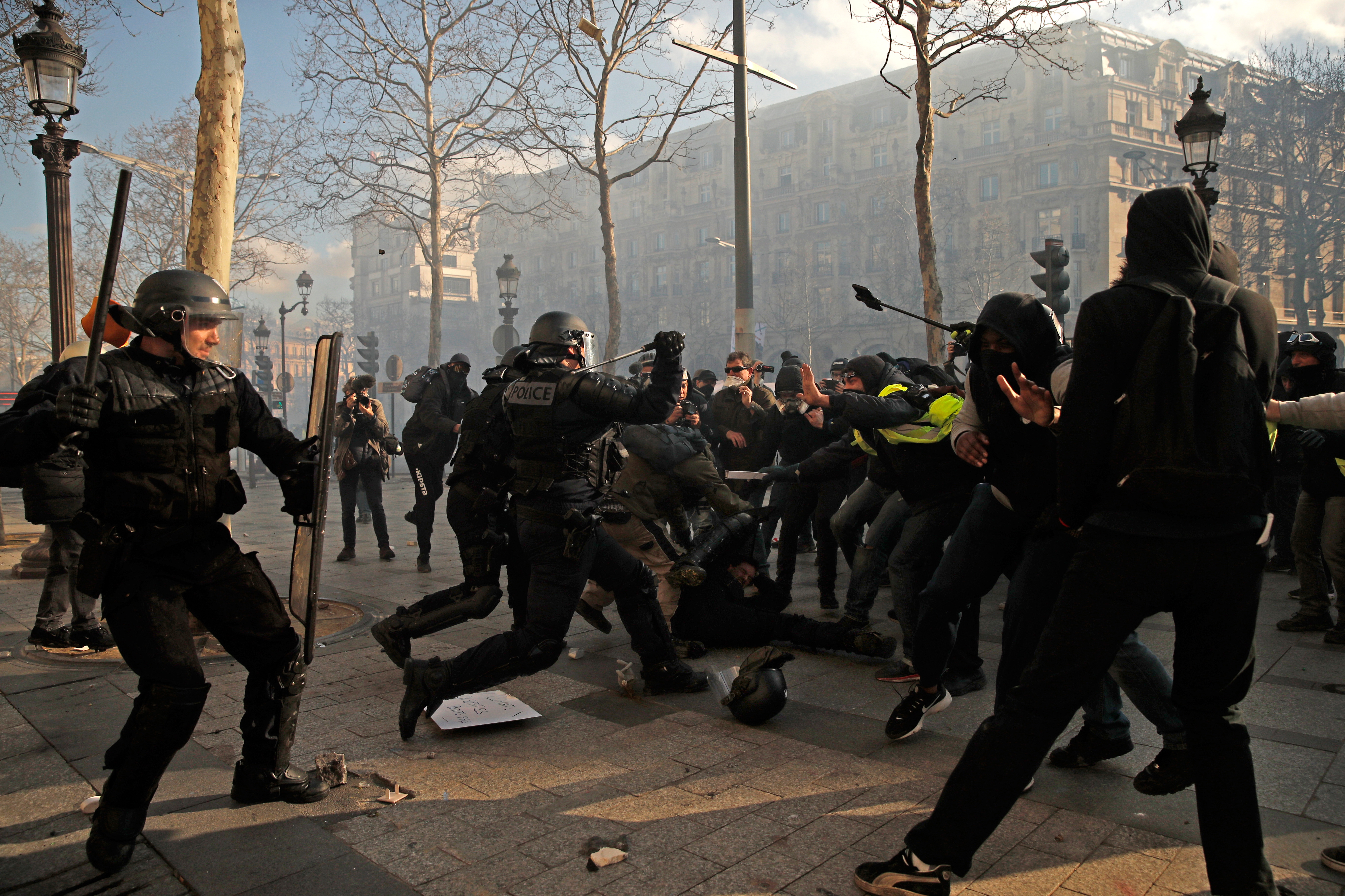 epa07443444 Yellow Vests protesters hit a riot police officer (C down) on the Champs Elysees during the 'Act XVIII' demonstration (the 18th consecutive national protest on a Saturday) in Paris, France, 16 March 2019. The so-called 'gilets jaunes' (yellow vests) is a grassroots protest movement with supporters from a wide span of the political spectrum, that originally started with protest across the nation in late 2018 against high fuel prices. The movement in the meantime also protests the French government's tax reforms, the increasing costs of living and some even call for the resignation of French President Emmanuel Macron.  EPA/YOAN VALAT