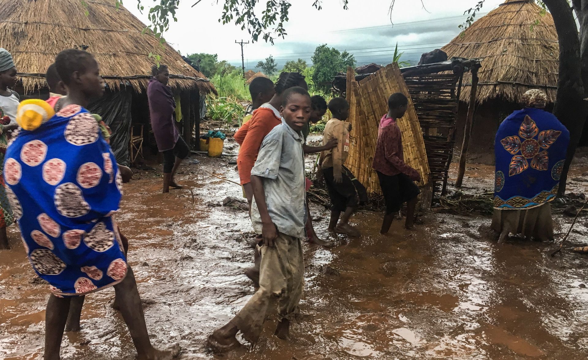 epa07446406 Inhabitants of Chiluvi, a village in central Mozambique, walk along a flooded and muddy street after Cyclone Idai and Floods that hit the region, in Nhamatanda, Mozambique, 13 March 2019 (Issued 18 March 2019). Chiluvo, together with Nhamatanda, Sofala, illustrates the tragedy that is experienced throughout the central region of Mozambique, especially in the provinces of Sofala and Manica, where there will already be between 73 and 84 confirmed deaths, according to official figures, leaving thousands in need of relief for remaining isolated in a flooded region.  EPA/ANDRE CATUEIRA BEST QUALITY AVAILABLE