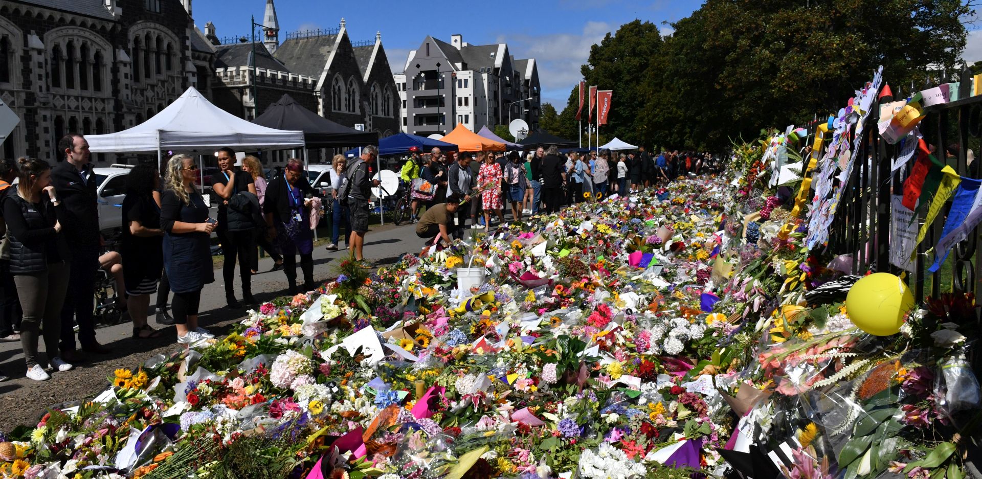 epa07447542 Members of the public looking at flowers at a makeshift memorial at the Botanical Gardens in Christchurch, New Zealand, 19 March 2019. A gunman killed 50 worshippers and injured 50 more at the Al Noor Masjid and Linwood Masjid on 15 March, 28-year-old Australian man, Brenton Tarrant, has appeared in court on 16 March and charged with murder.  EPA/MICK TSIKAS  AUSTRALIA AND NEW ZEALAND OUT