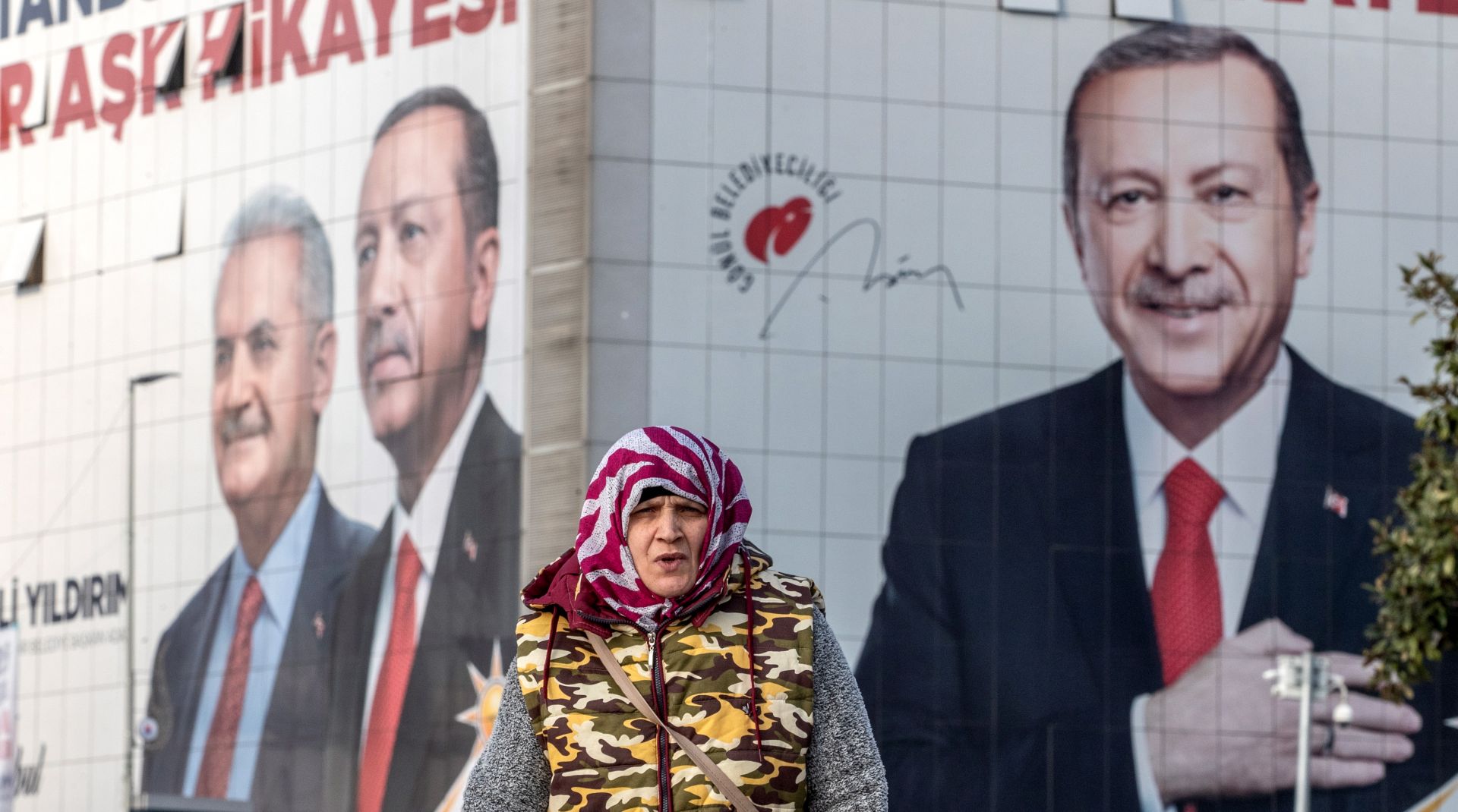 epa07467143 A woman walks in front of the pictures of Turkish President Recep Tayyip Erdogan (R) and Candidate of Justice and Development Party (AK Party) for Istanbul mayor Binali Yildirim (L), in Istanbul, Turkey, 27 March 2019. Local elections in Turkey's capital and the country's overall 81 provinces are scheduled for 31 March 2019.  EPA/SEDAT SUNA
