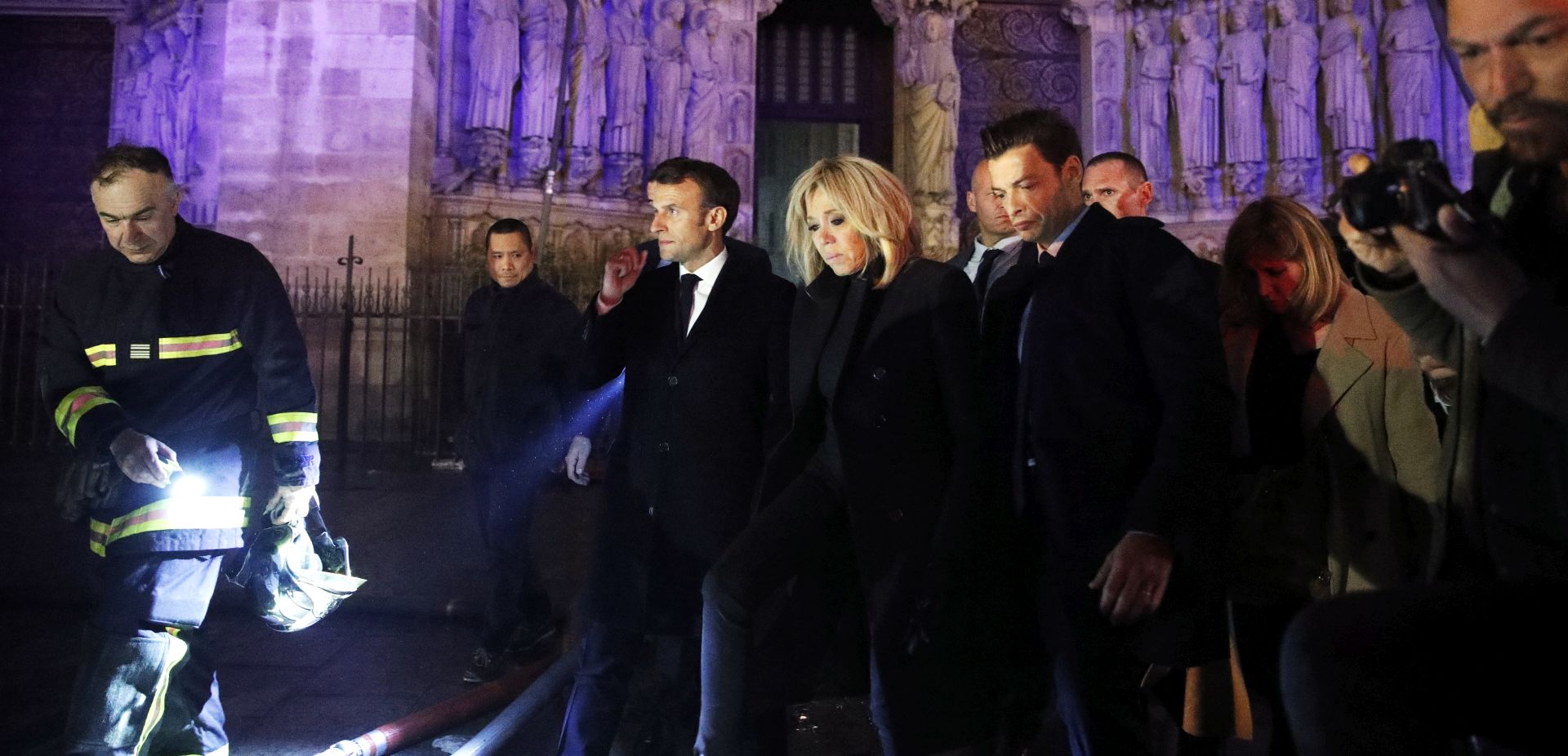 epa07509136 French President Emmanuel Macron (C) and his wife Brigitte Macron (R) pay a visit to firemen fighting against a fire burning the roof of the Notre-Dame cathedral in Paris, France, 15 April 2019. A fire started in the late afternoon in one of the most visited monuments of the French capital.  EPA/YOAN VALAT