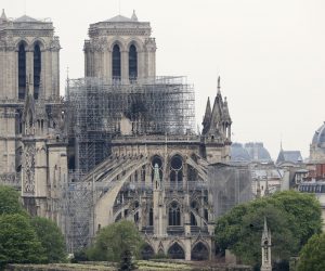 epa07509655 The statue of Saint Genevieve (front), Patron Saint of Paris, on le Pont de la Tournelle bridge, rises near the damaged Notre-Dame Cathedral after a massive fire that destroyed its roof in Paris, France, 16 April 2019. View from the Arab World Institute. A fire started in the late afternoon 15 April in one of the most visited monuments of the French capital.  EPA/CHRISTOPHE PETIT TESSON