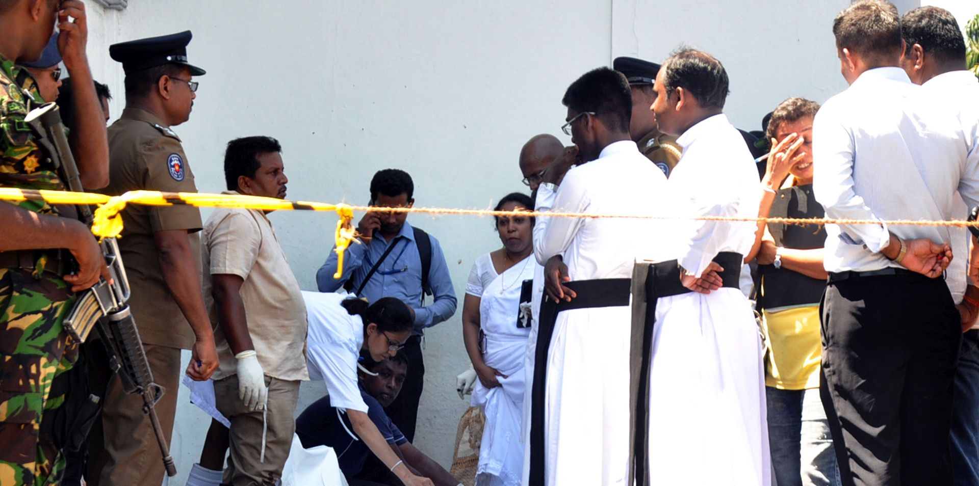 epa07519598 Policemen and priests look on as rescue workers evacuate remains of victims at the scene after an explosion hit at St Anthony's Church in Kochchikade in Colombo, Sri Lanka, 21 April 2019. According to news reports at least 138 people killed and over 400 injured in a series of blasts during the Easter Sunday service at St Anthony's Church in Kochchikade, Shangri-La Hotel and Kingsbury Hotel with many more places. EPA/M.A. PUSHPA KUMARA