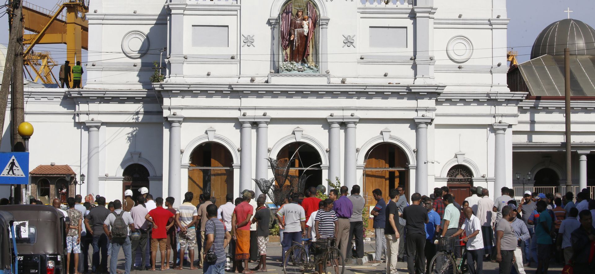 epa07520941 Sri Lankan people stand outside St. Anthony's Church in Kochchikade, Colombo, Sri Lanka, 22 April 2019. According to news reports, at least 290 people have been killed and over 500 injured in a series of blasts during Easter Sunday service at churches and hotels across Colombo on 21 April.   EPA/M.A. PUSHPA KUMARA