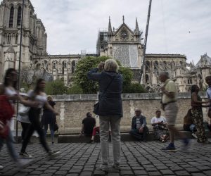 epa07521521 Tourists near Notre Dame de Paris cathedral after a new smaller security area was applied by the French police in Paris, France, 22 April 2019. A fire started in the late afternoon 15 April in one of the most visited monuments of the French capital.  EPA/Julien de Rosa