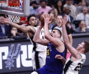 epa07528825 Denver Nuggets player Nikola Jokic of Serbia (C) goes to the basket against San Antonio Spurs players Derrick White (L) and Jakob Poeltl of Austria (R) during the NBA Western Conference Playoffs game six at the AT&T Center in San Antonio, Texas, USA, 25 April 2019.  EPA/LARRY W. SMITH SHUTTERSTOCK OUT