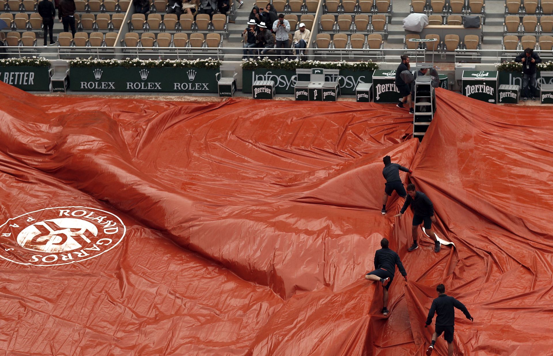 epa07633303 Staff covers the Court Philippe Chatrier as rain interrupts Dominic Thiem of Austria playing Novak Djokovic of Serbia during their men’s semi final match during the French Open tennis tournament at Roland Garros in Paris, France, 07 June 2019.  EPA/YOAN VALAT