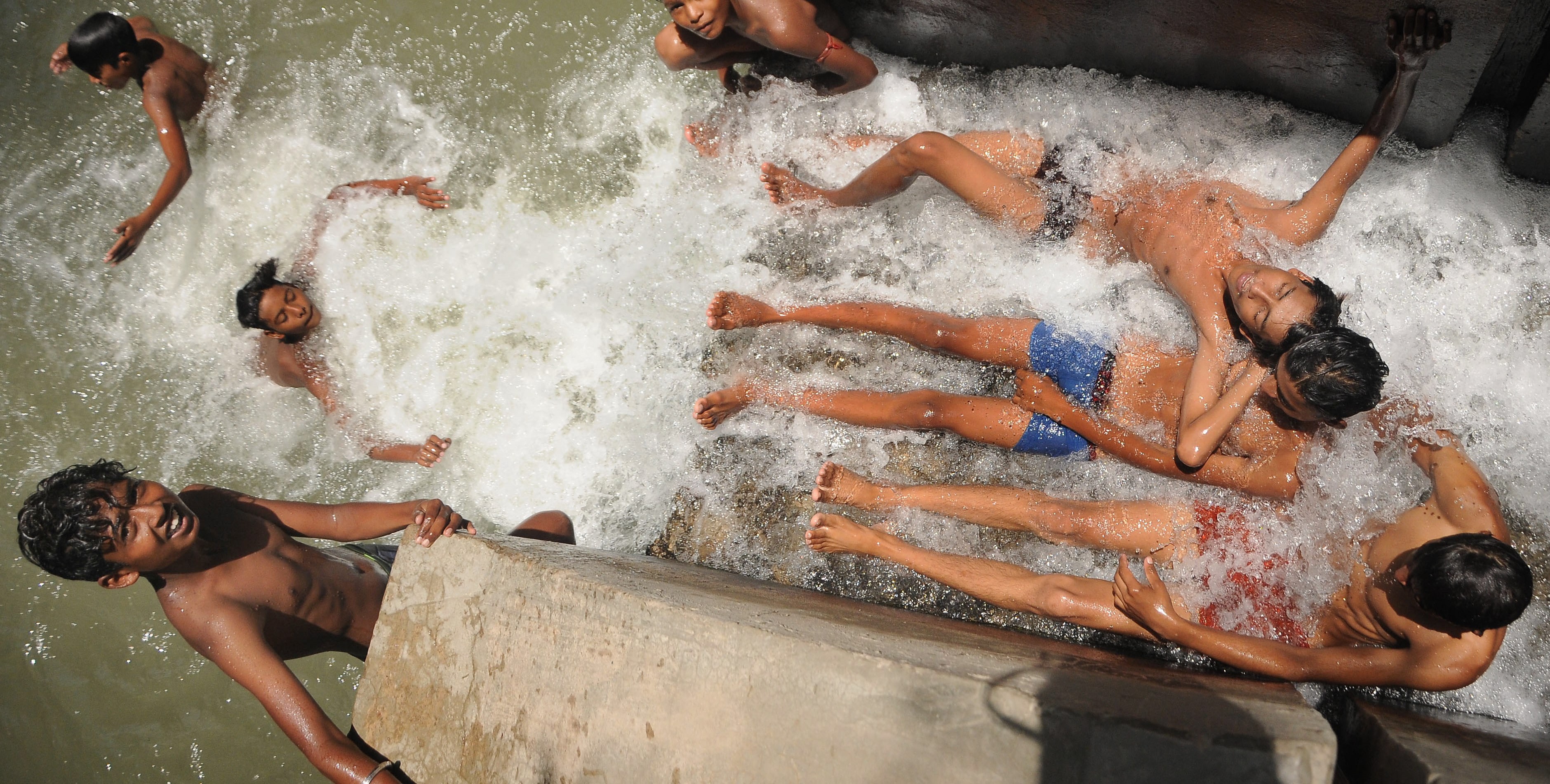 epa07638406 Indian boys cool off at a canal in New Delhi, India, 10 June 2019. The forecasts predict hot weather in the Indian capital with the maximum temperature at 46 degrees Celsius.   EPA/STR