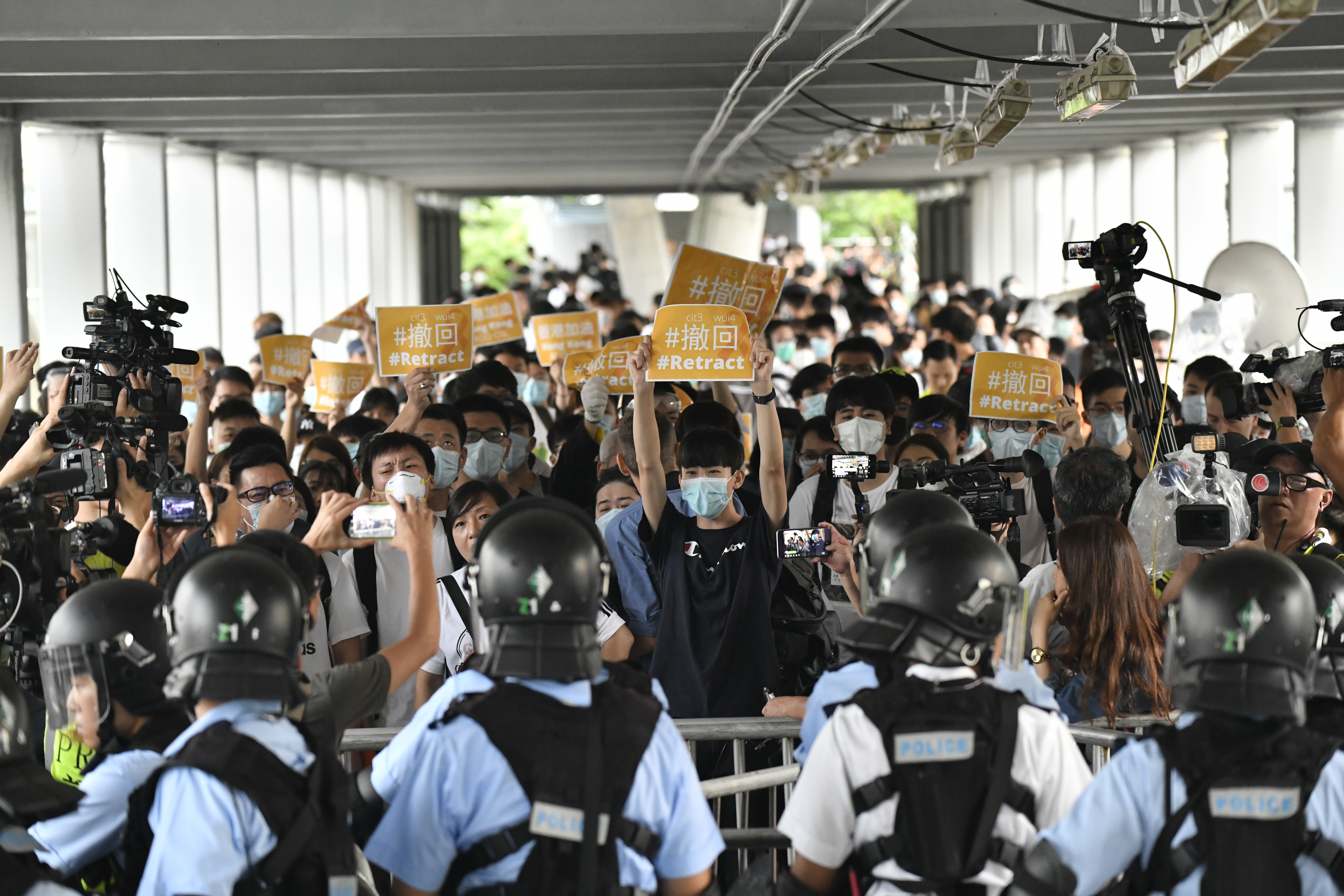 epa07645149 Protesters holds signs in front of police officers a day after a violent protest against an extradition law in Hong Kong, China, 13 June 2019. The Hong Kong Legislative Council on 13 June postponed for the second consecutive day a debate on a controversial extradition bill in the aftermath of violent clashes where riot police fired rubber bullets, tear gas and pepper spray at protesters.  EPA/EDWIN KWOK