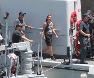 epa07686970 Rescue ship 'Sea-Watch 3' captain Carola Rackete (C), who is being held on charges of abetting immigration and ramming a police cutter, is escorted as she arrives in Porto Empedocle, Italy, 01 July 2019. German captain Carola Rackete was arrested on 29 June reportedly after violating orders from the Italian Finance Police and entering the port of Lampedusa while ramming a patrol boat on migrant rescue ship 'Sea-Watch 3'.  EPA/PASQUALE CLAUDIO MONTANA LAMPO