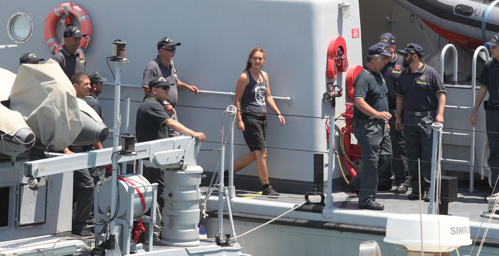 epa07686970 Rescue ship 'Sea-Watch 3' captain Carola Rackete (C), who is being held on charges of abetting immigration and ramming a police cutter, is escorted as she arrives in Porto Empedocle, Italy, 01 July 2019. German captain Carola Rackete was arrested on 29 June reportedly after violating orders from the Italian Finance Police and entering the port of Lampedusa while ramming a patrol boat on migrant rescue ship 'Sea-Watch 3'.  EPA/PASQUALE CLAUDIO MONTANA LAMPO