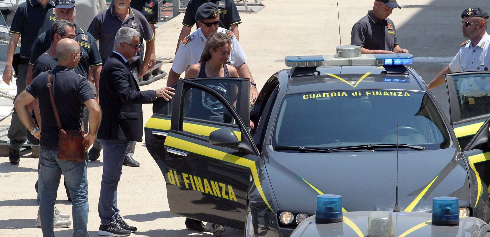 epa07686966 Rescue ship 'Sea-Watch 3' captain Carola Rackete (C), who is being held on charges of abetting immigration and ramming a police cutter, boards a car of the Guardia di Financia upon her arrival at Porto Empedocle, Italy, 01 July 2019. German captain Carola Rackete was arrested on 29 June reportedly after violating orders from the Italian Finance Police and entering the port of Lampedusa while ramming a patrol boat on migrant rescue ship 'Sea-Watch 3'.  EPA/PASQUALE CLAUDIO MONTANA LAMPO
